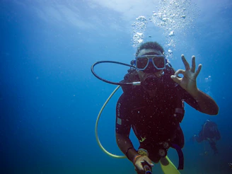 Scuba diver gives ok sign underwater with bubbles.