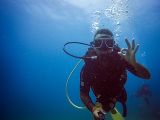 Scuba diver gives ok sign underwater with bubbles.
