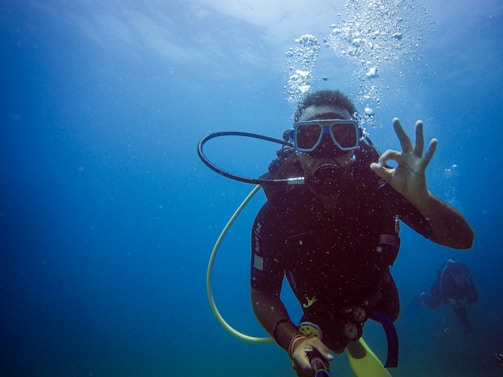 Scuba diver gives ok sign underwater with bubbles.