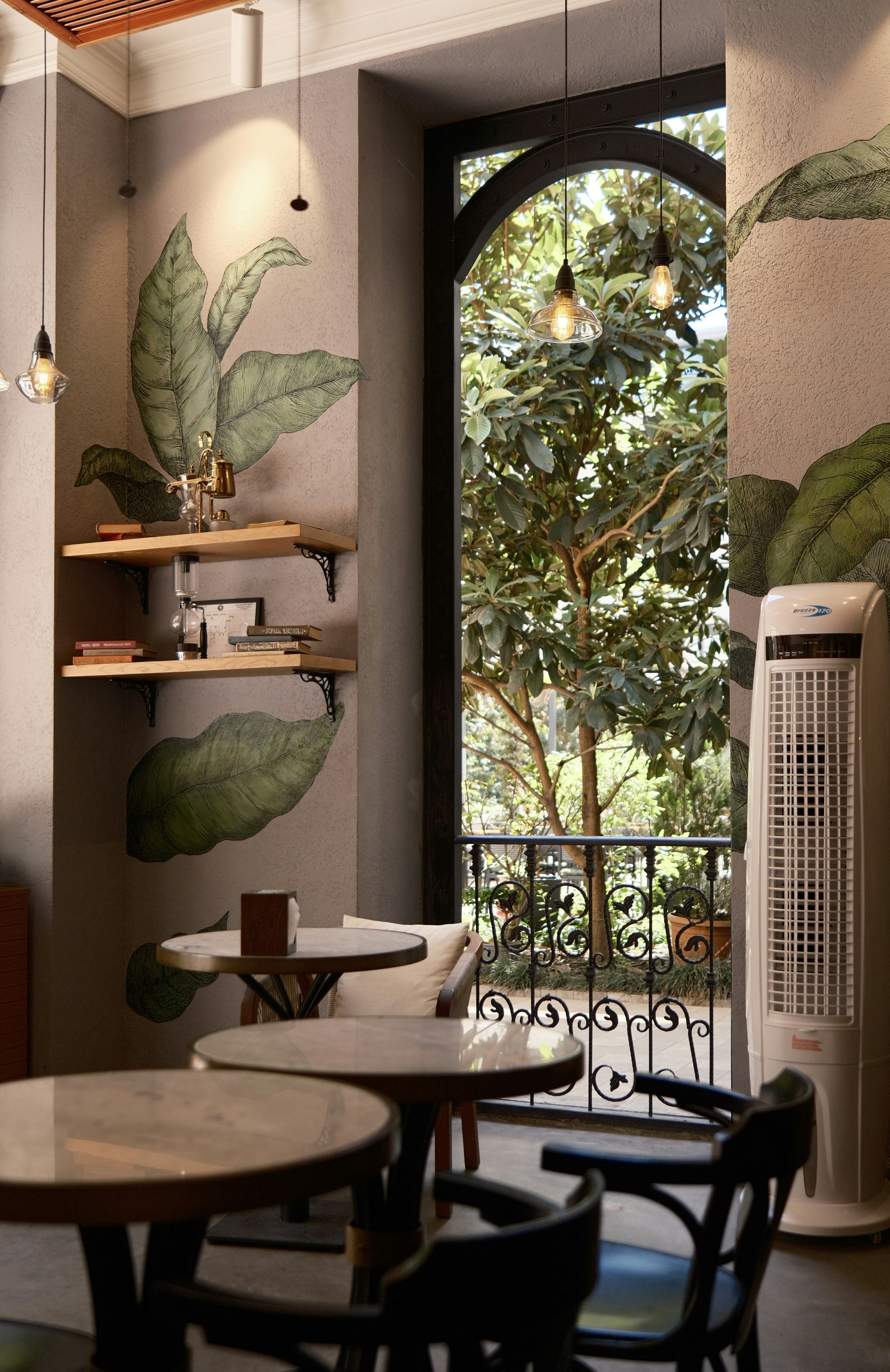 테이블, 의자, 대형 식물 벽화가 있는 카페 인테리어.