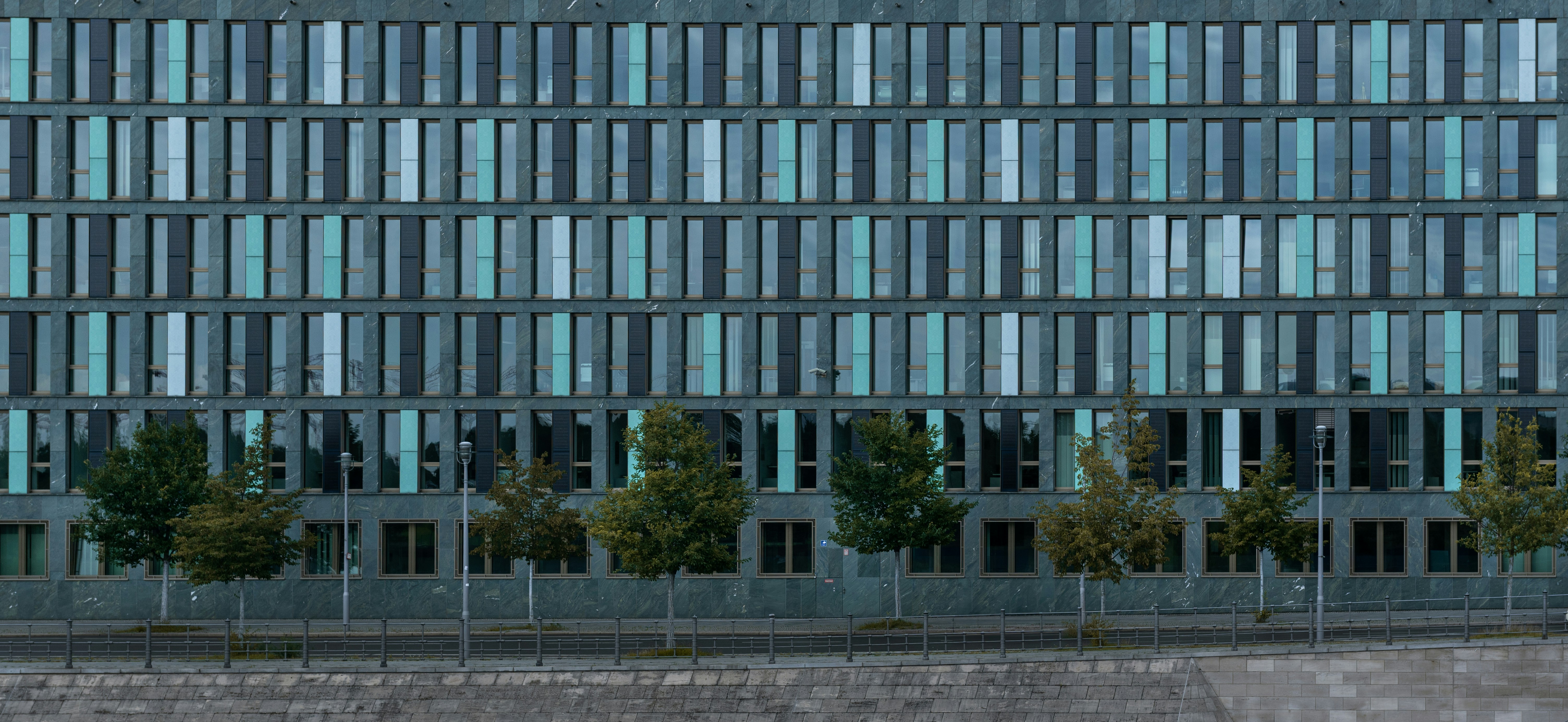 Modern office building with repeating windows and trees.