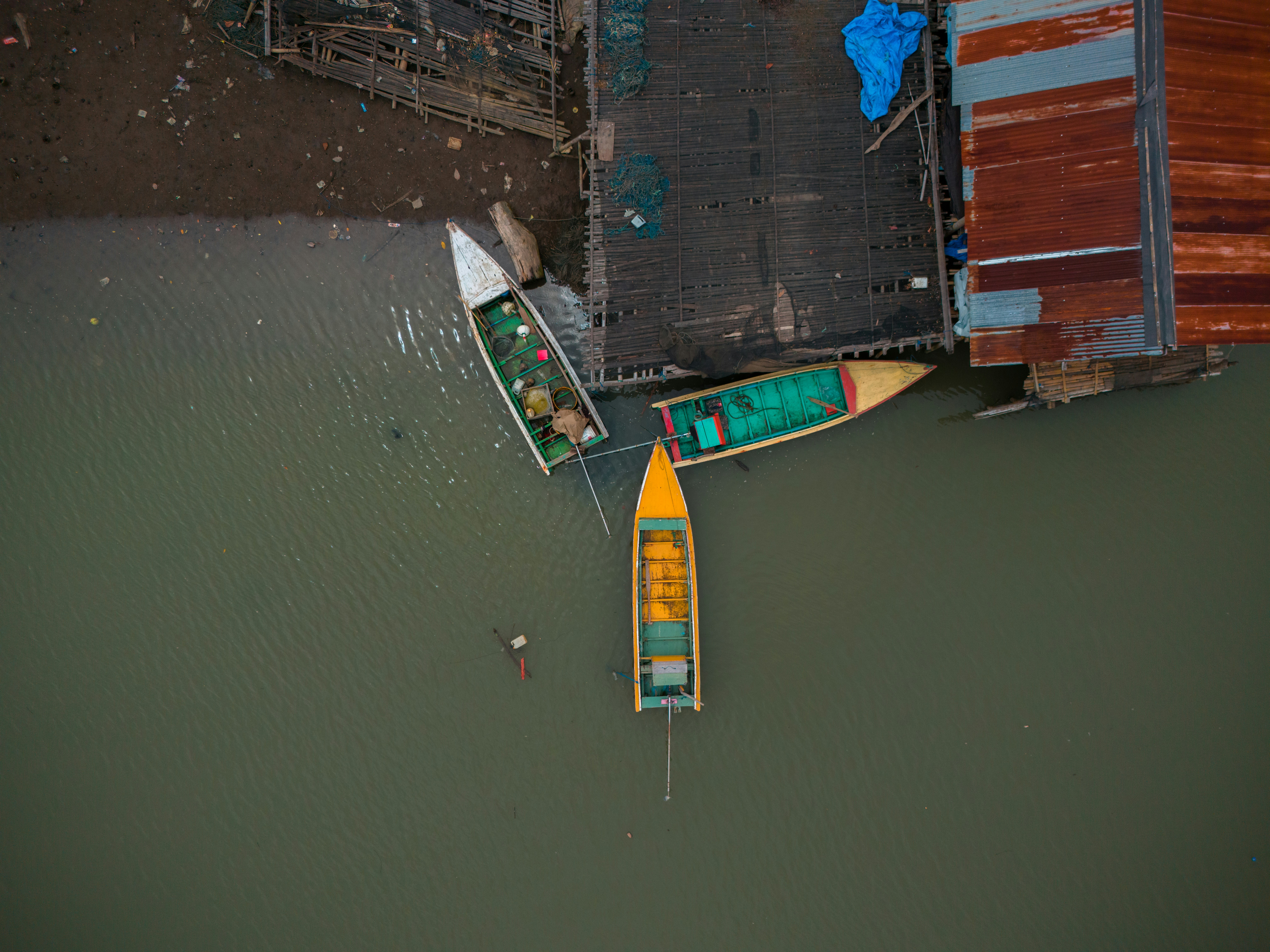 Three boats docked near a weathered pier