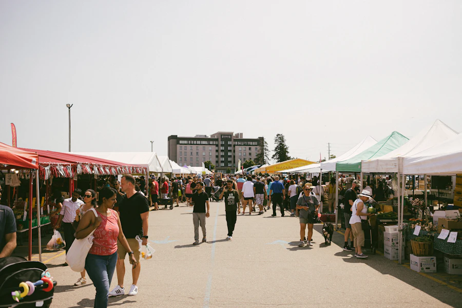 Shoppers strolling between market tents on a sunny day