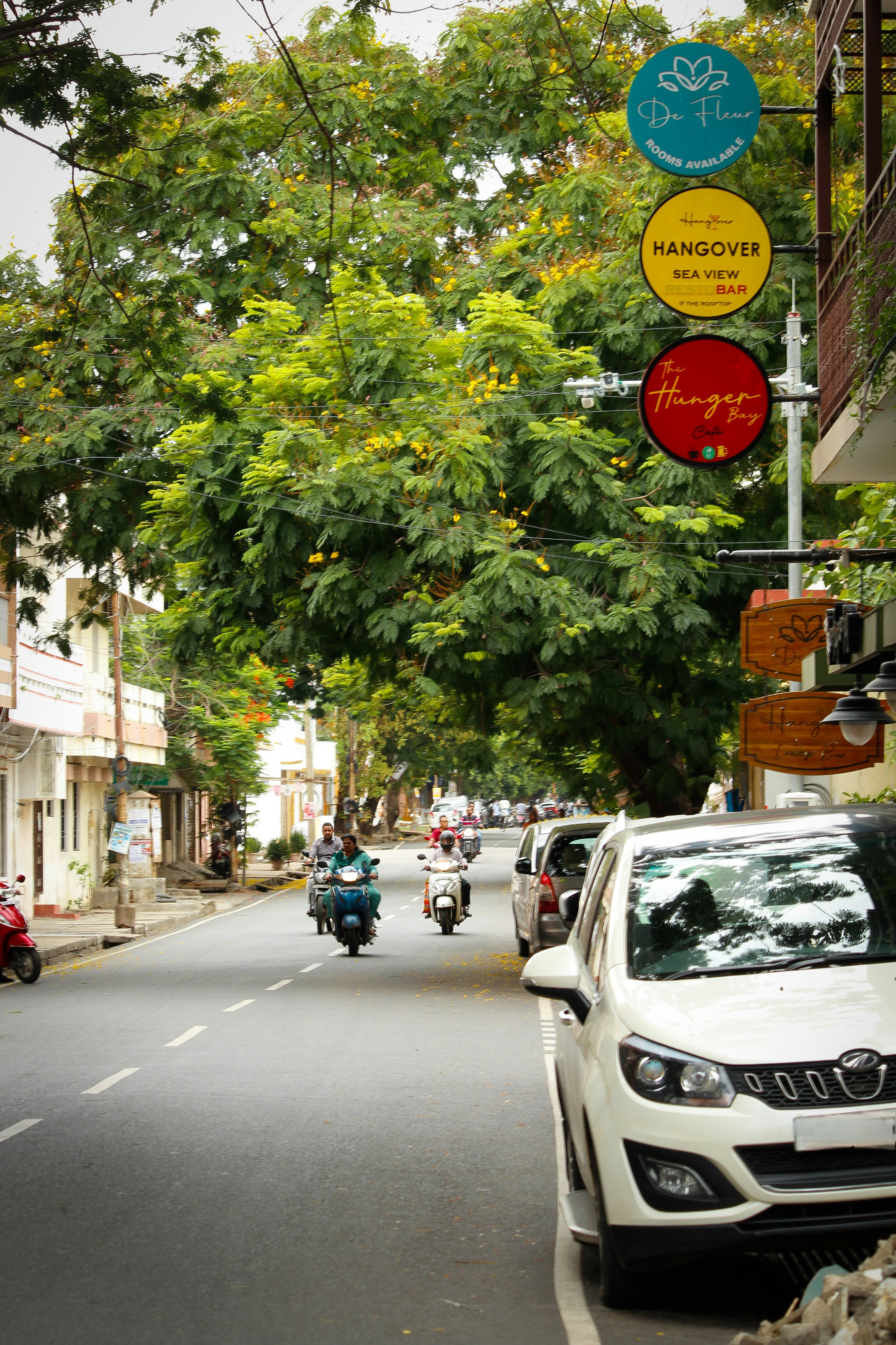 Street with parked car, scooters, and signs.