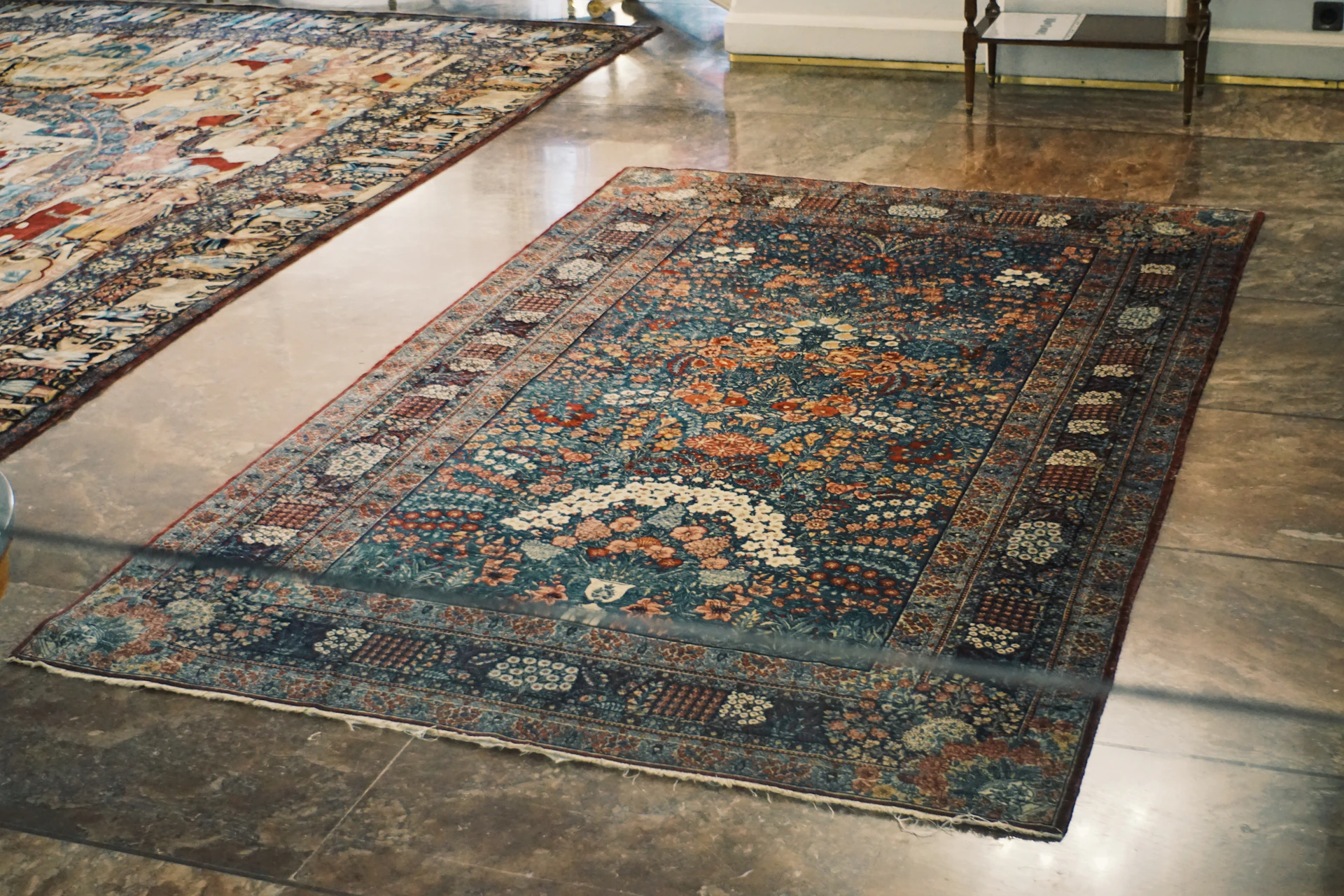 An ornate persian rug displayed on a polished floor