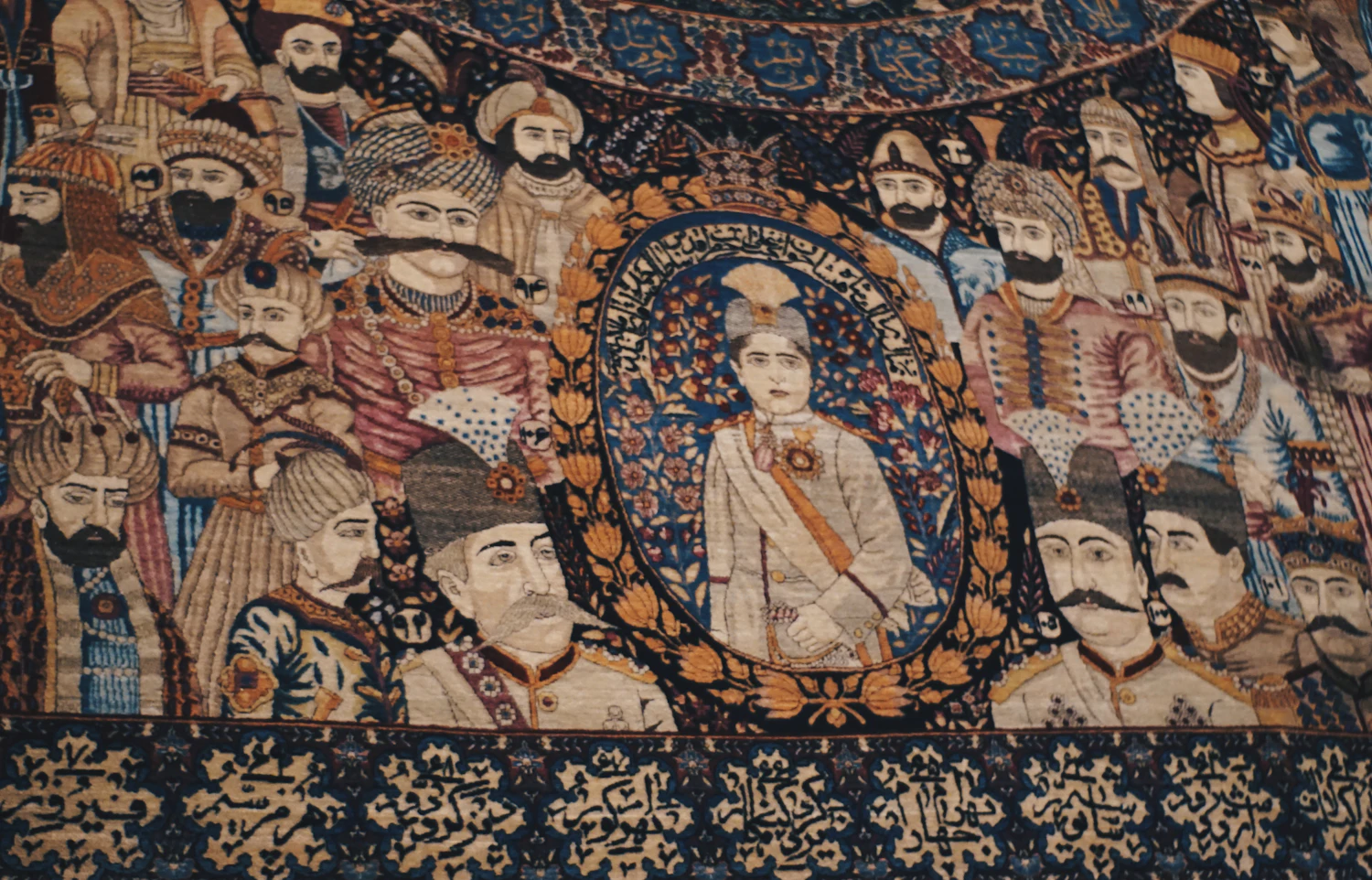 A woven tapestry crowded with court figures around a central portrait