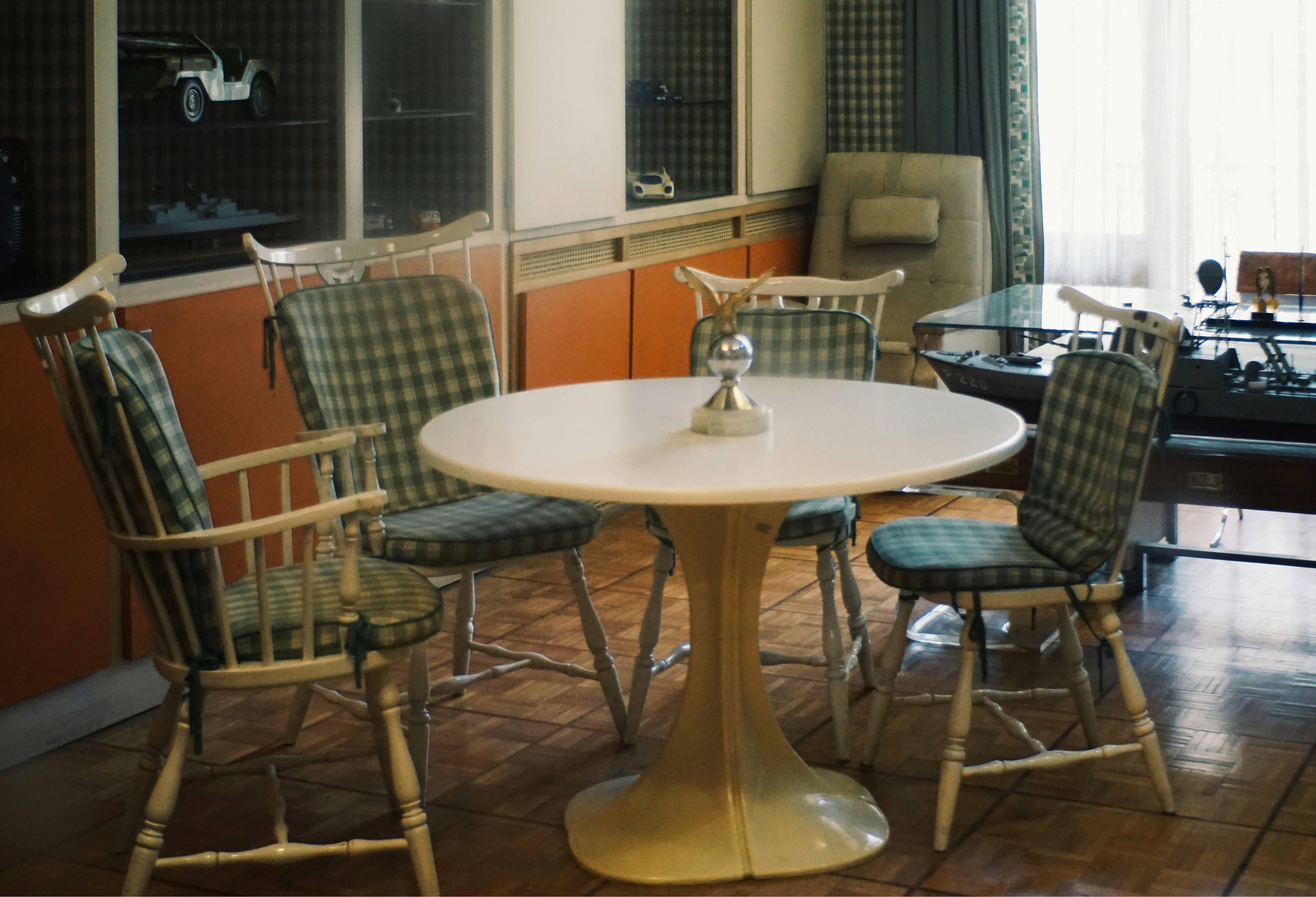 Round table with four plaid chairs in a room.