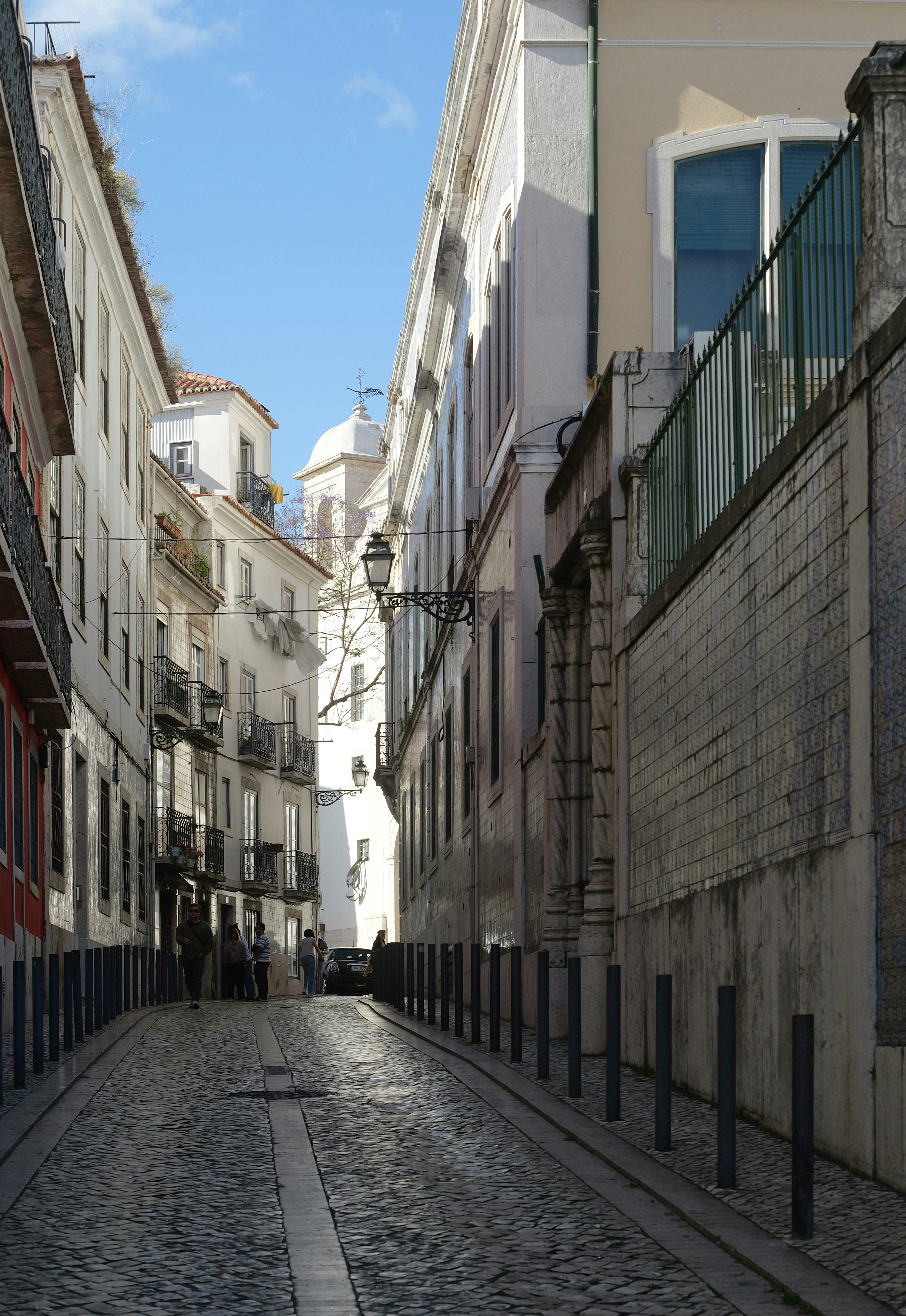 Rua de paralelepípedos ladeada por edifícios sob um céu azul
