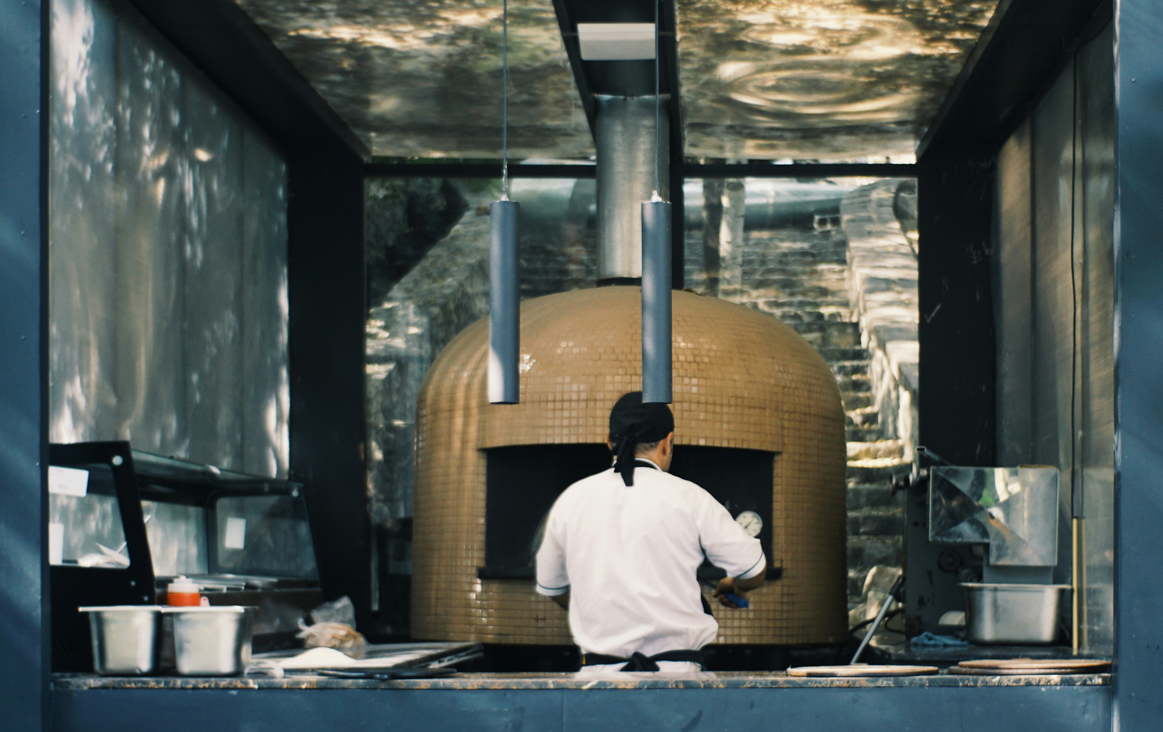 Chef preparing food near large pizza oven