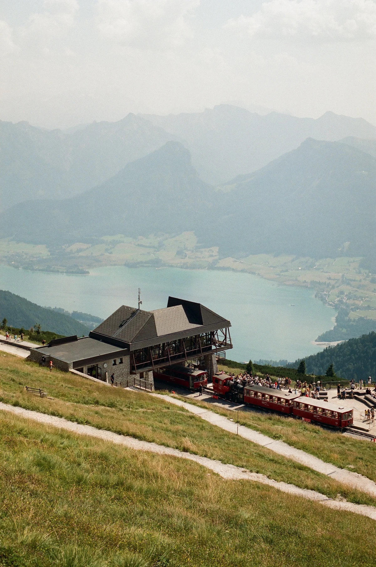 The railway station high on the Schafberg with a red train at the platform, above a lake and mountains