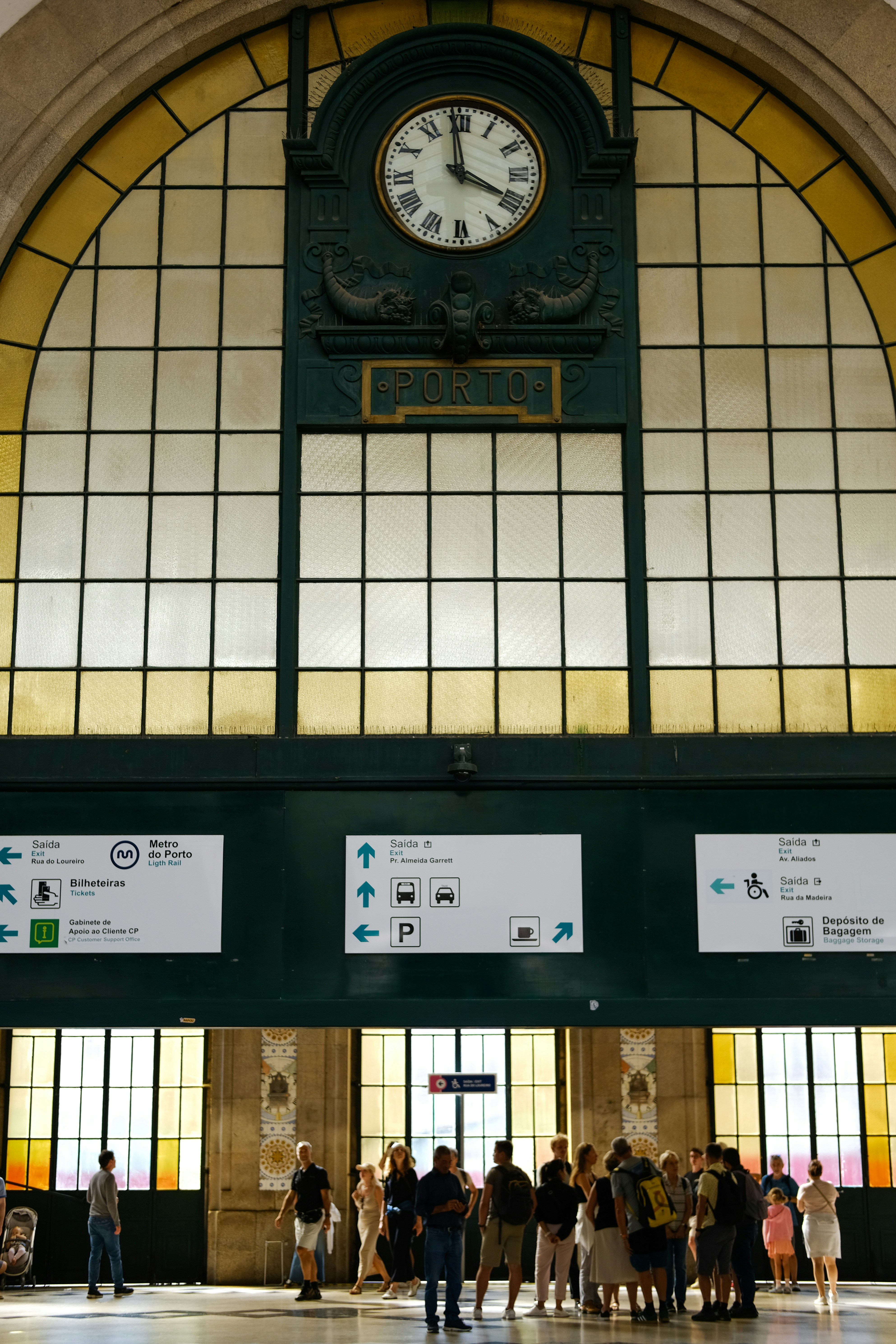 People gathered inside a grand train station with large clock.