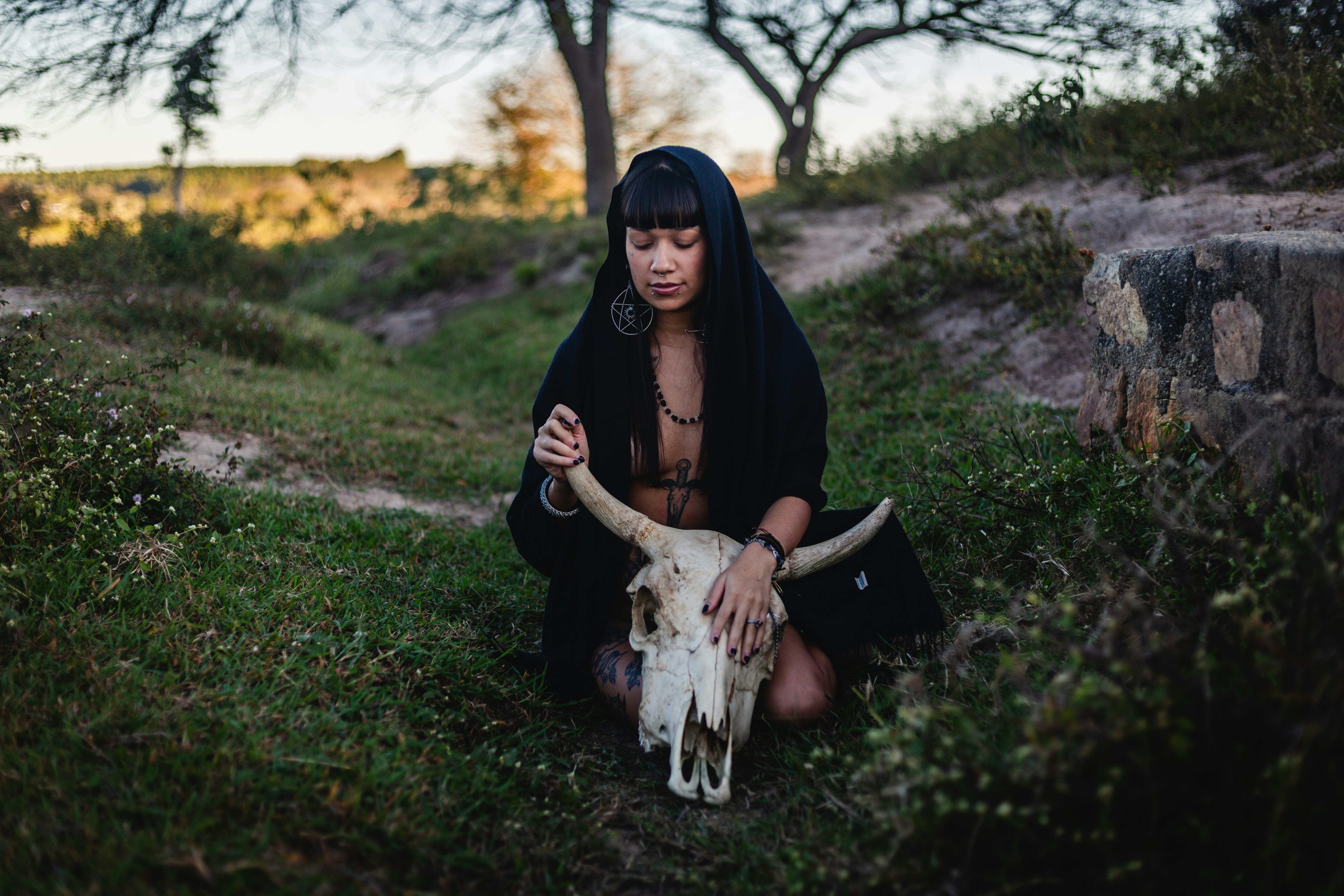 Woman in black holding a bull skull outdoors.