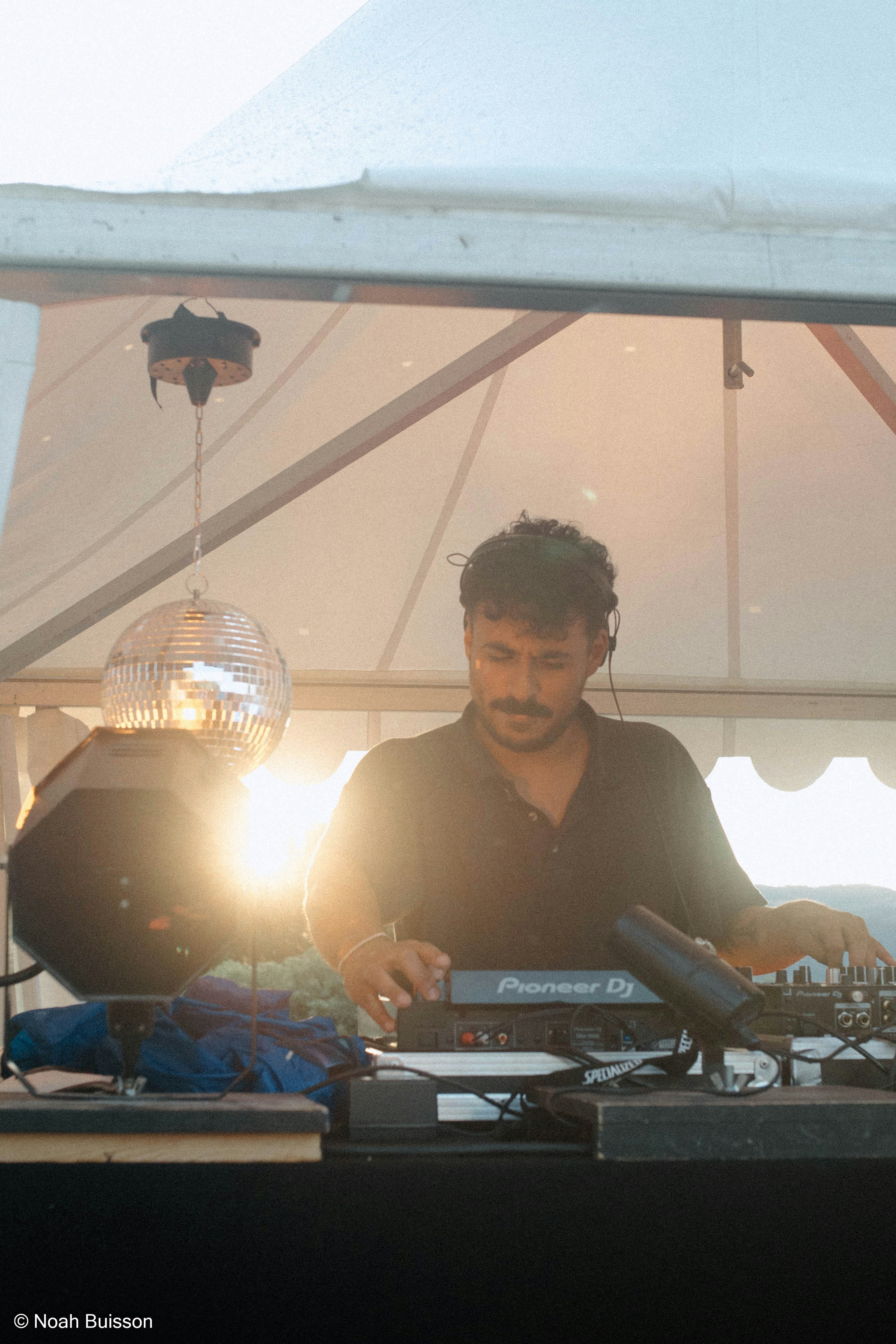 A DJ performing on stage, seen from the crowd.