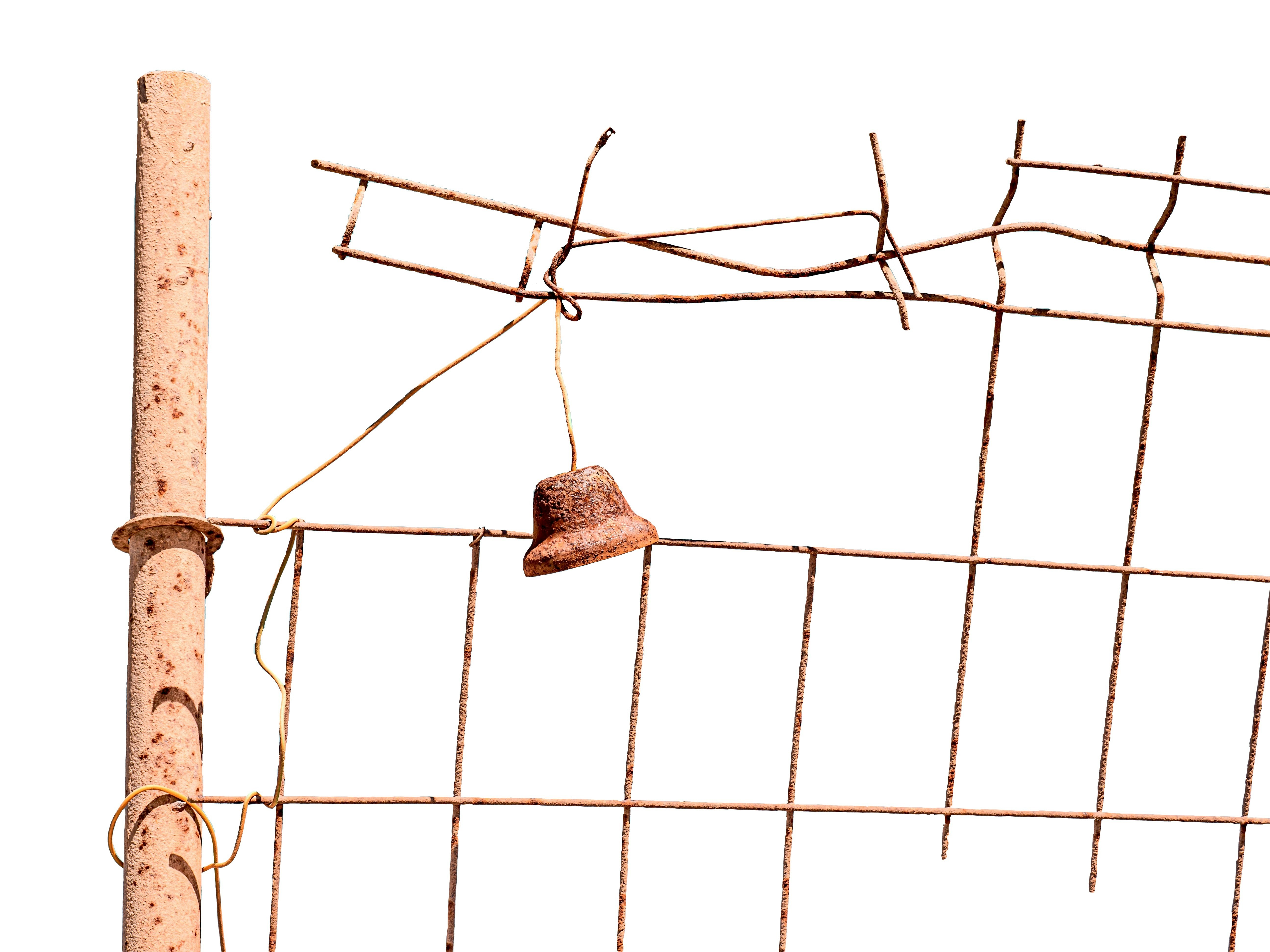 Rusty bell hanging from a wire fence