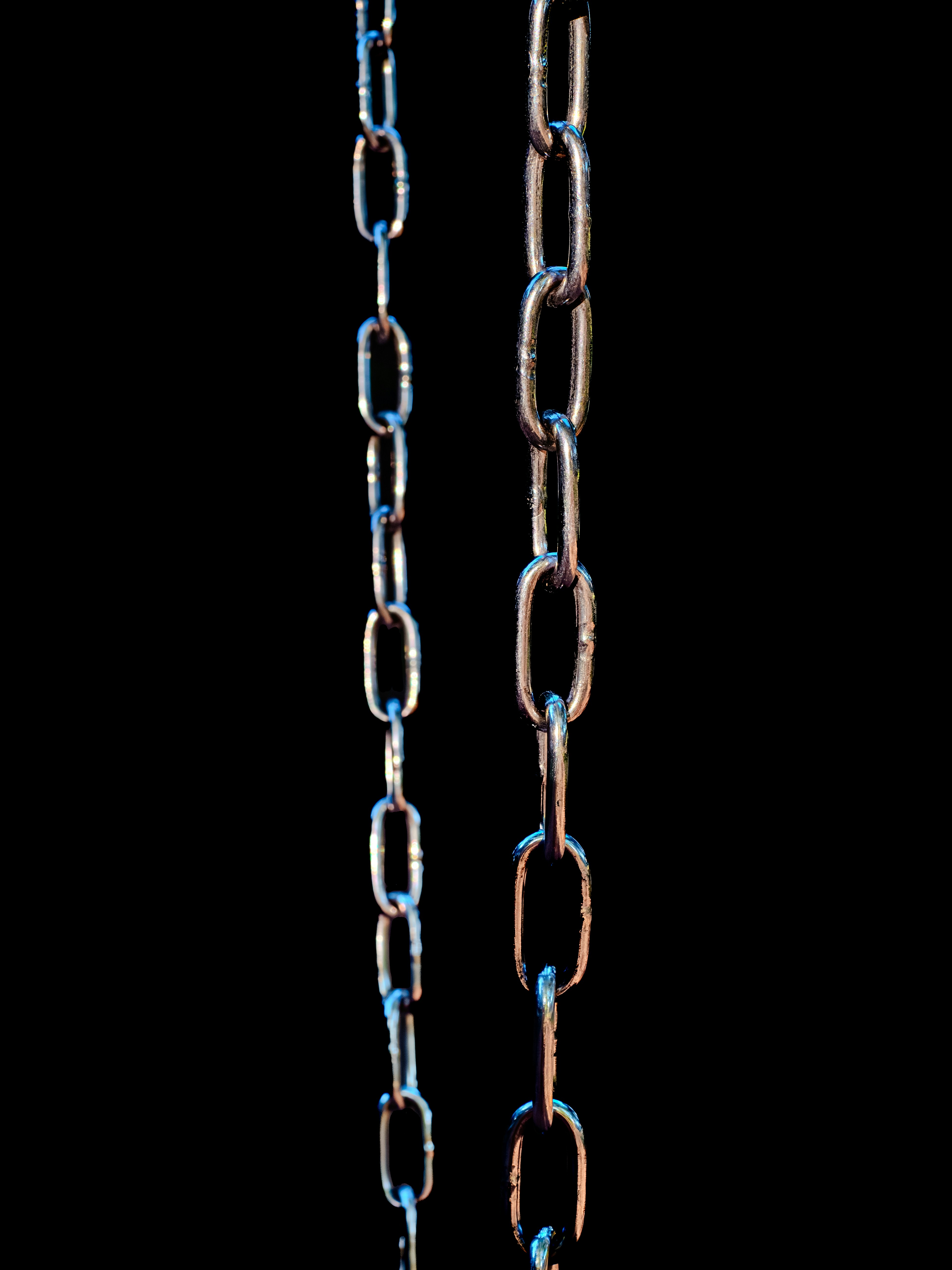 Two metal chains hanging against black background