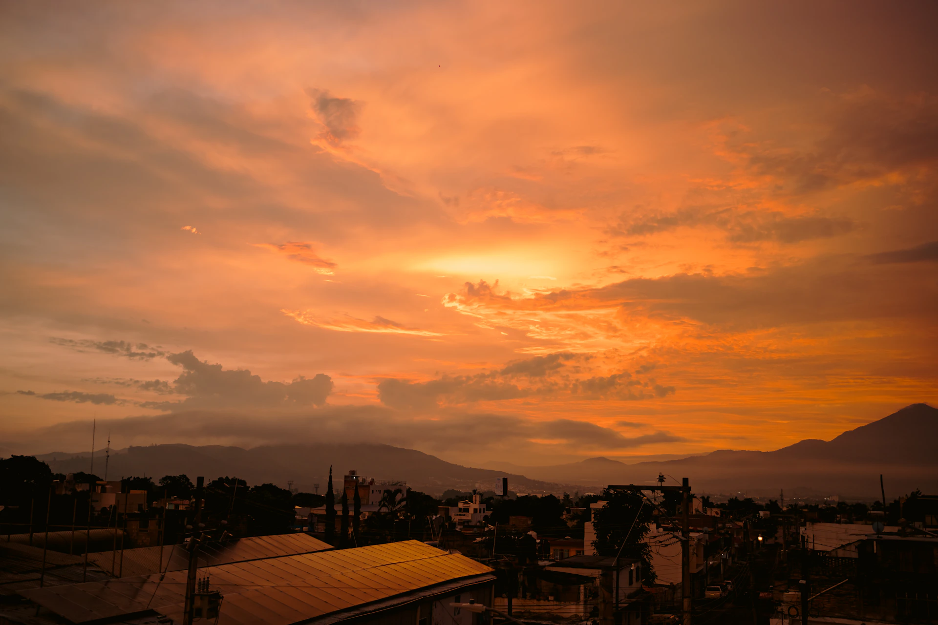 Vibrant orange sky over mountains at sunset.
