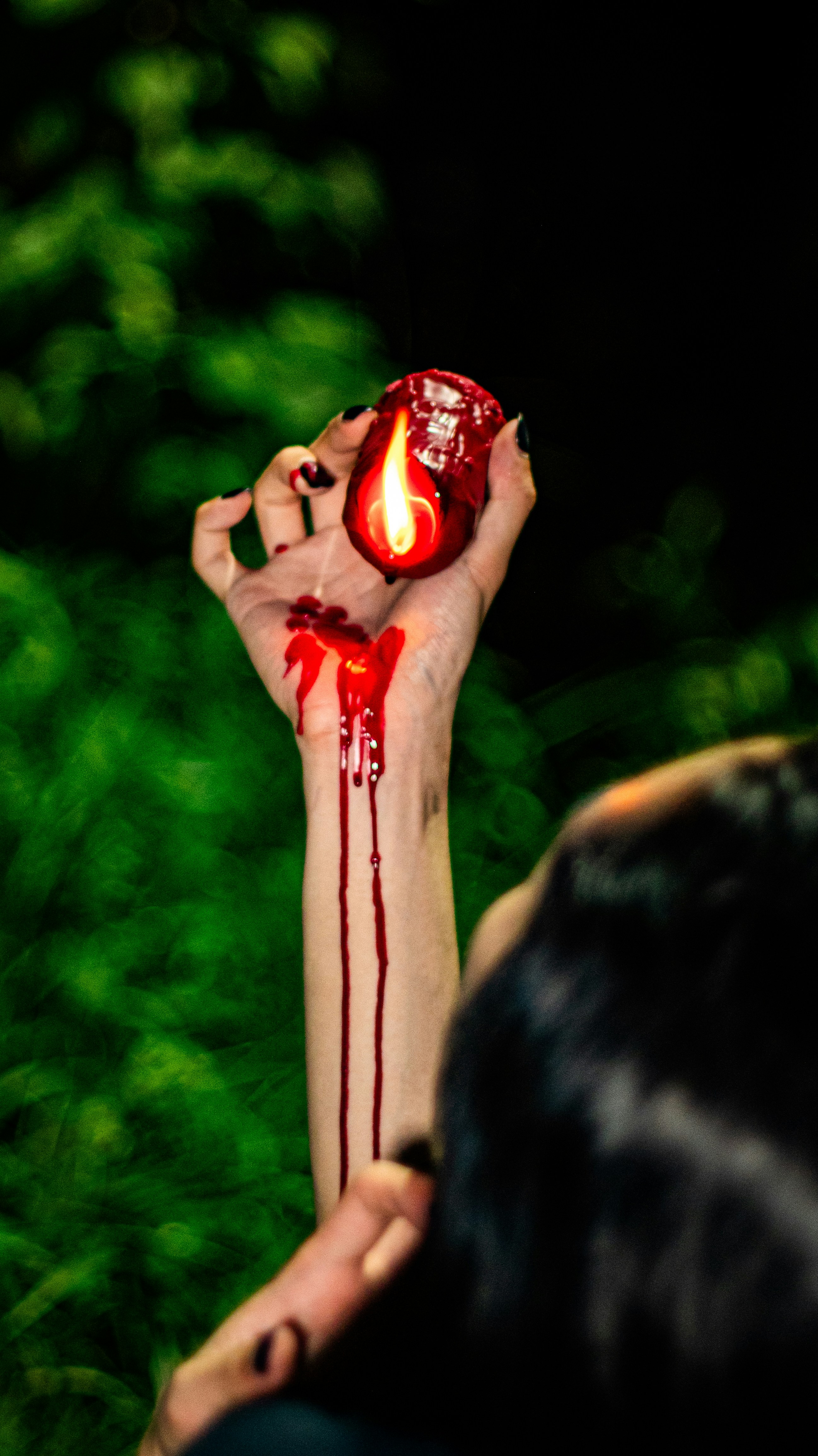 Hand holding a bloody candle with dripping blood.