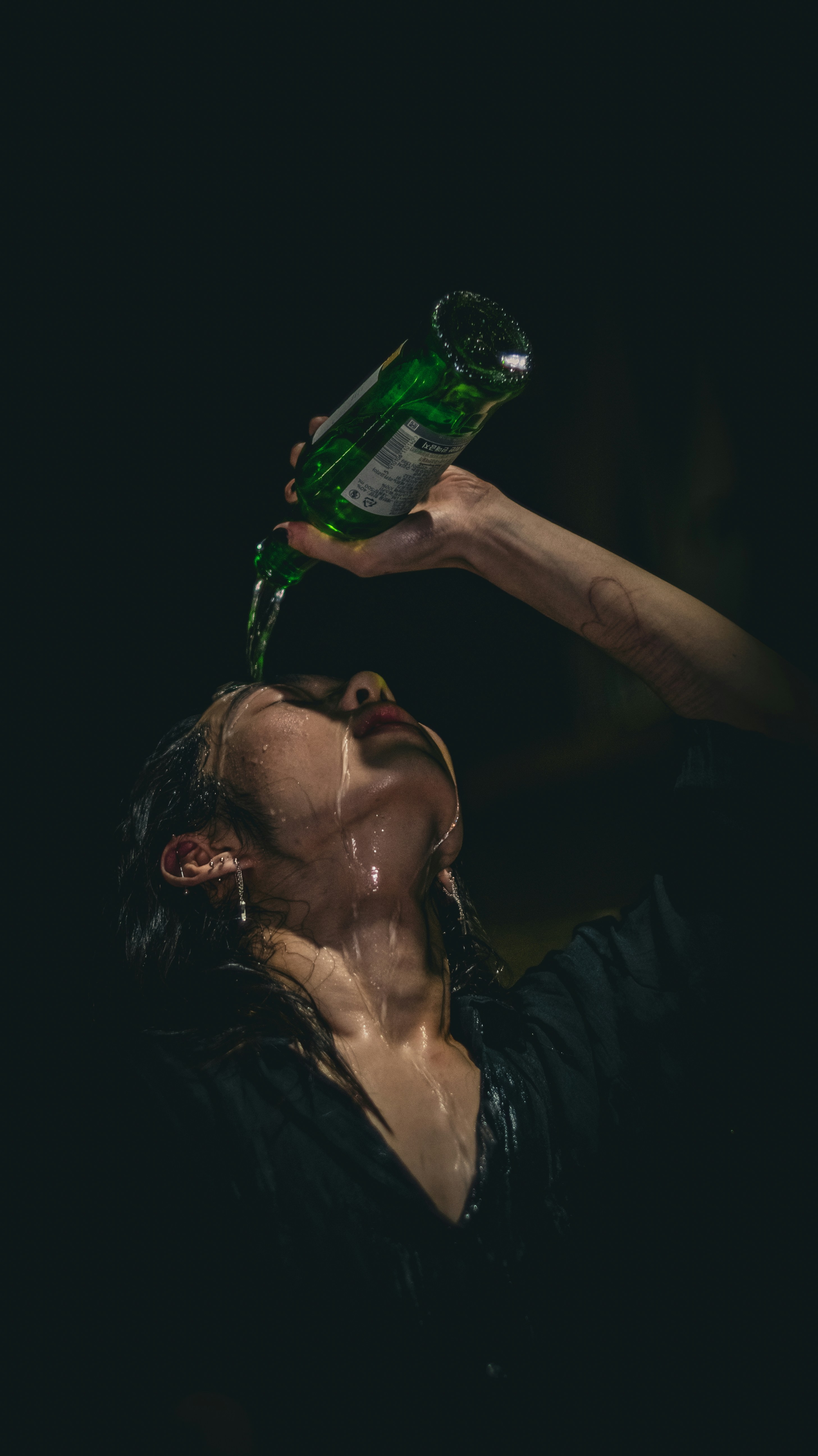Woman pouring water from bottle onto her face