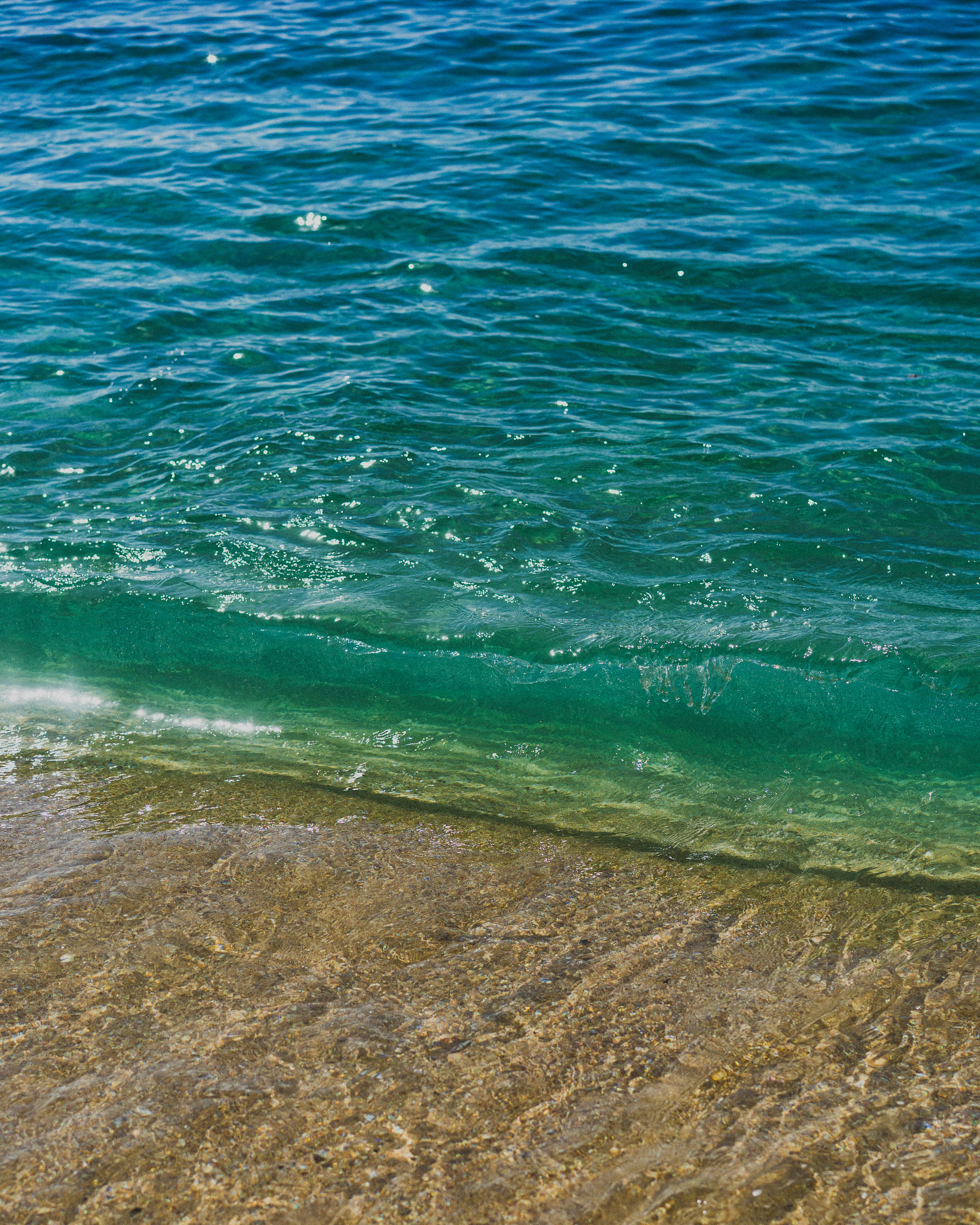Clear turquoise water laps gently onto a sandy beach.