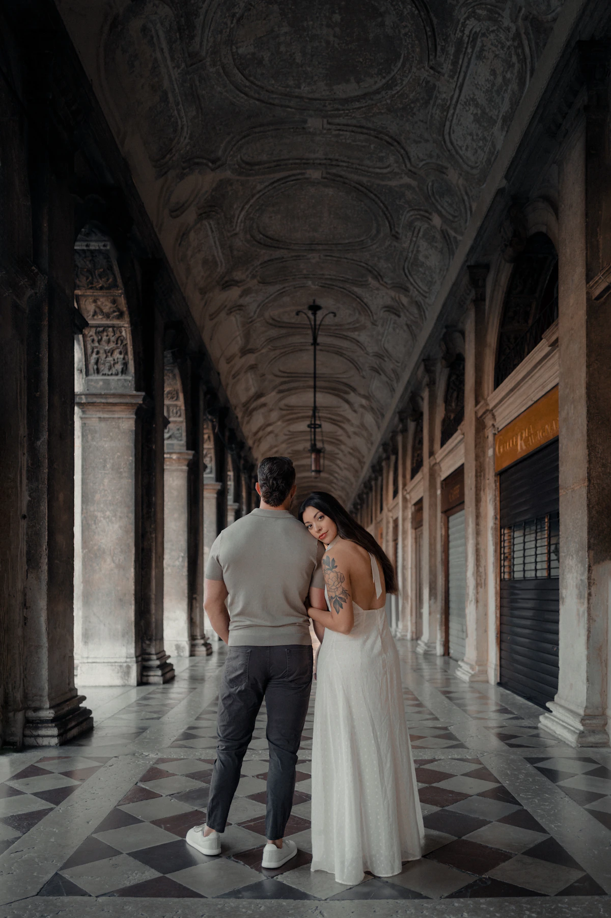 A couple walking down a grand arched hallway
