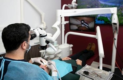 Dentist using microscope on patient in dental chair.