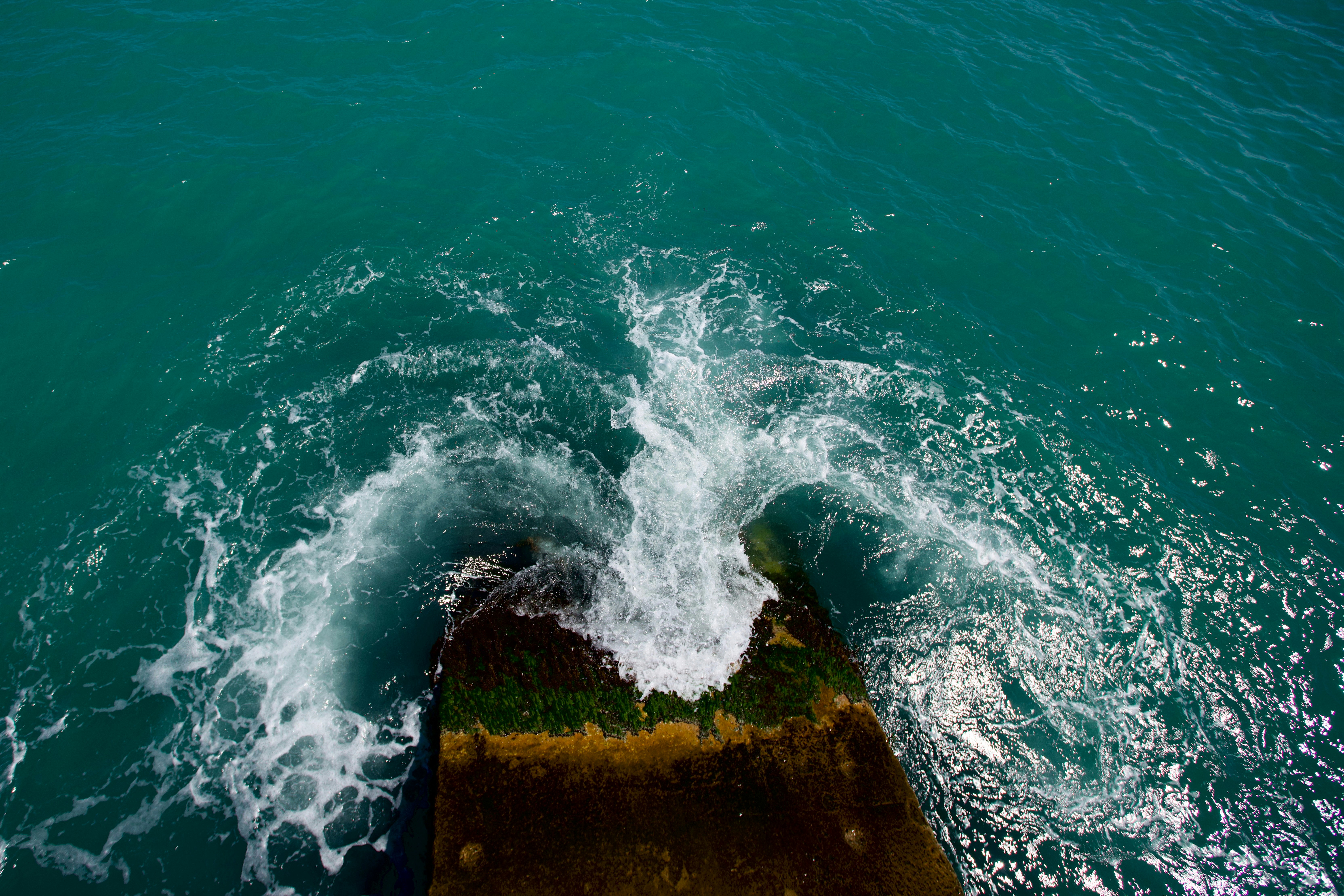 Waves crashing against a concrete structure in the ocean.