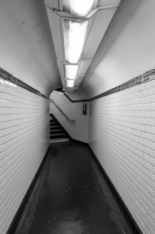A dimly lit subway tunnel with white tiled walls.