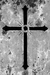 Ornate cross with sunburst design on weathered surface