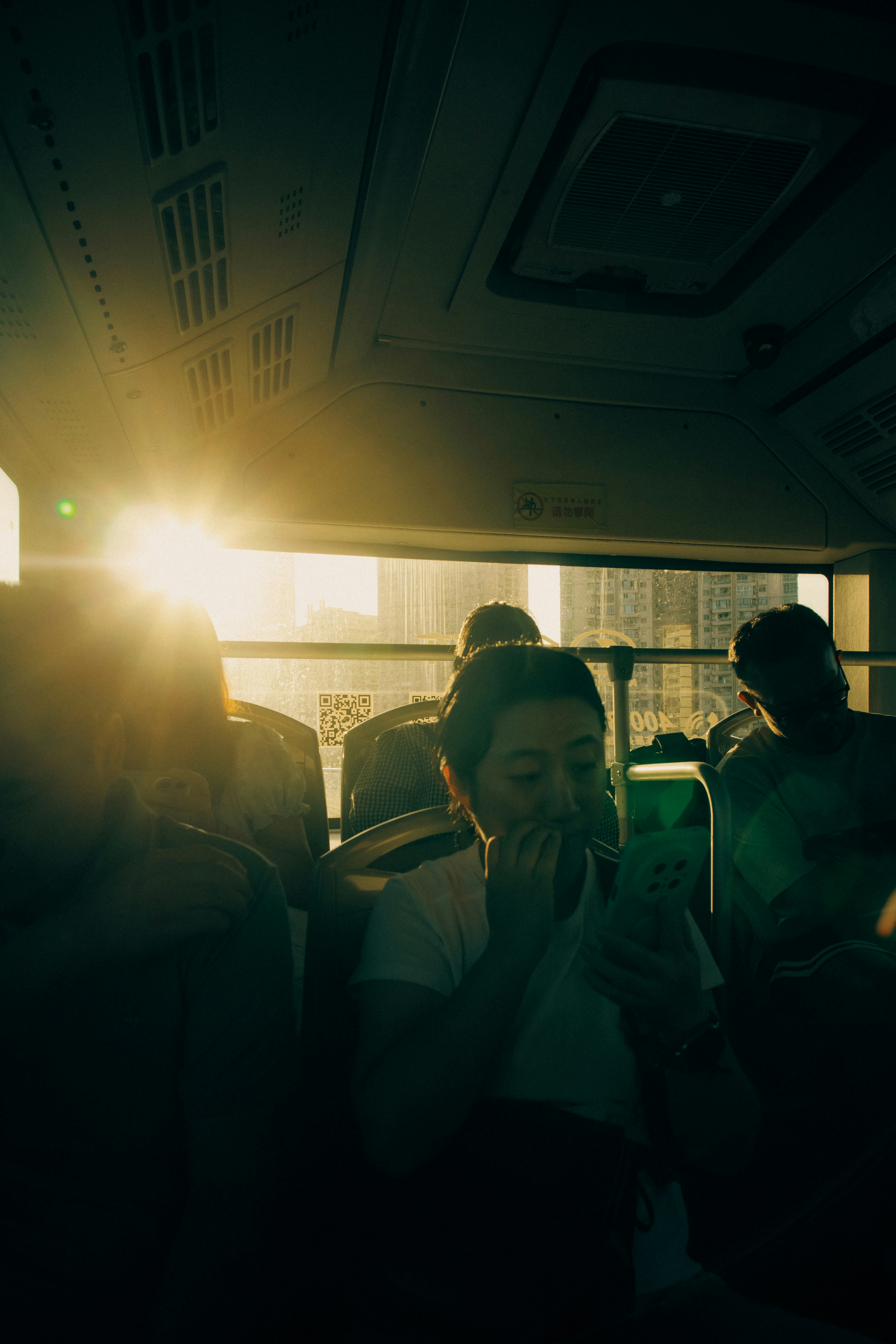 Sunlight streams through bus window illuminating passengers.