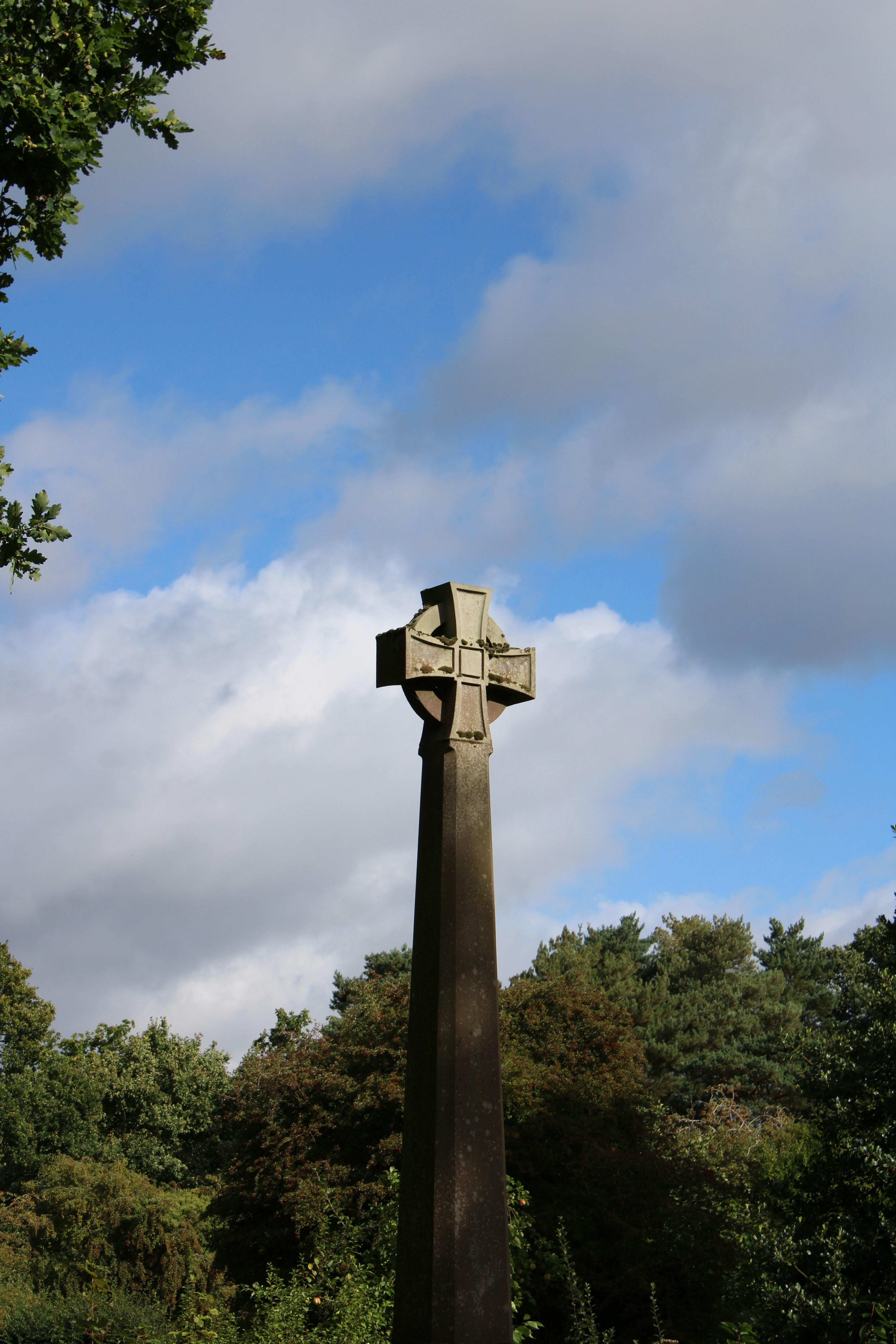 Croce celtica in pietra contro un cielo azzurro nuvoloso