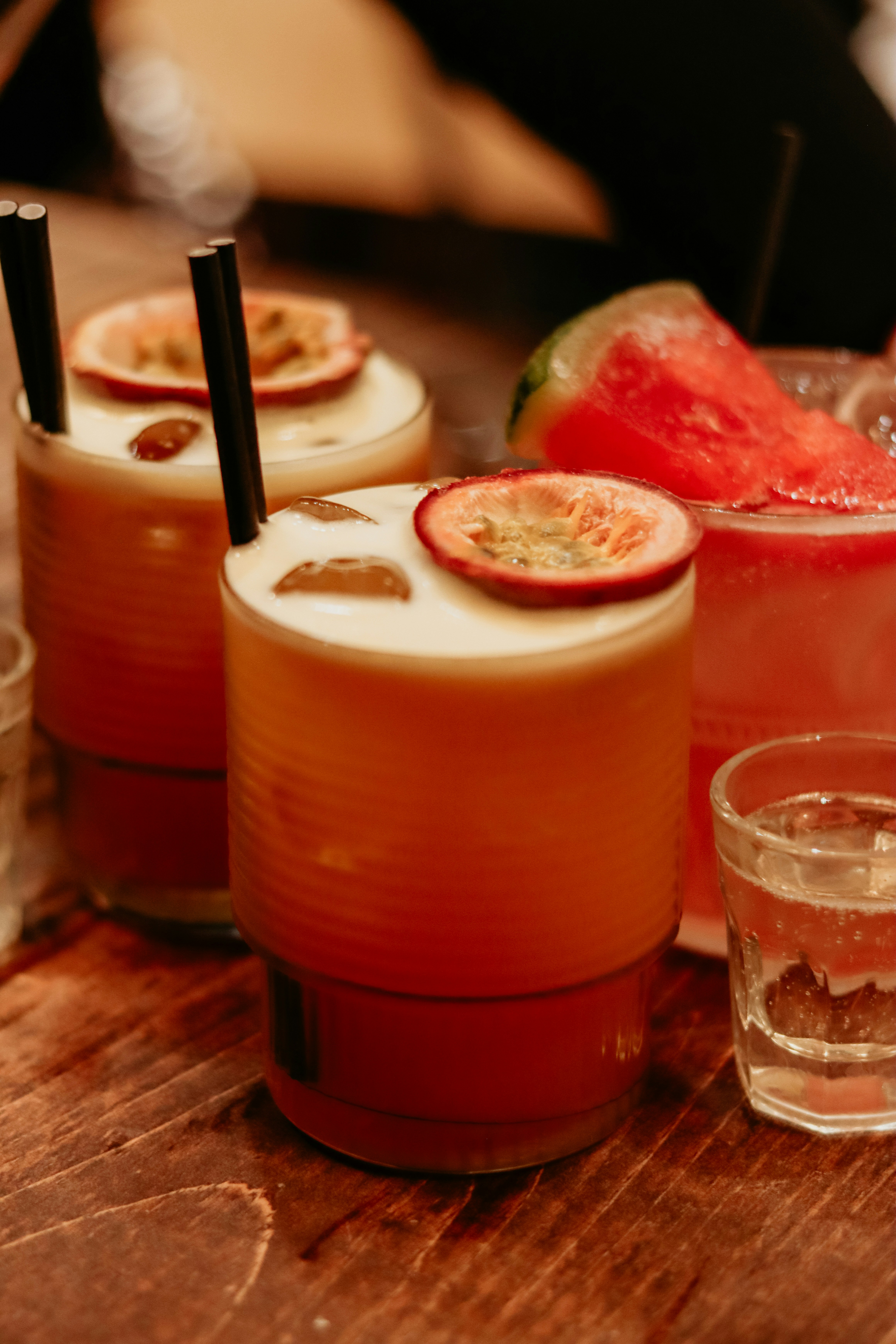 Trois cocktails colorés garnis de tranches de fruits.