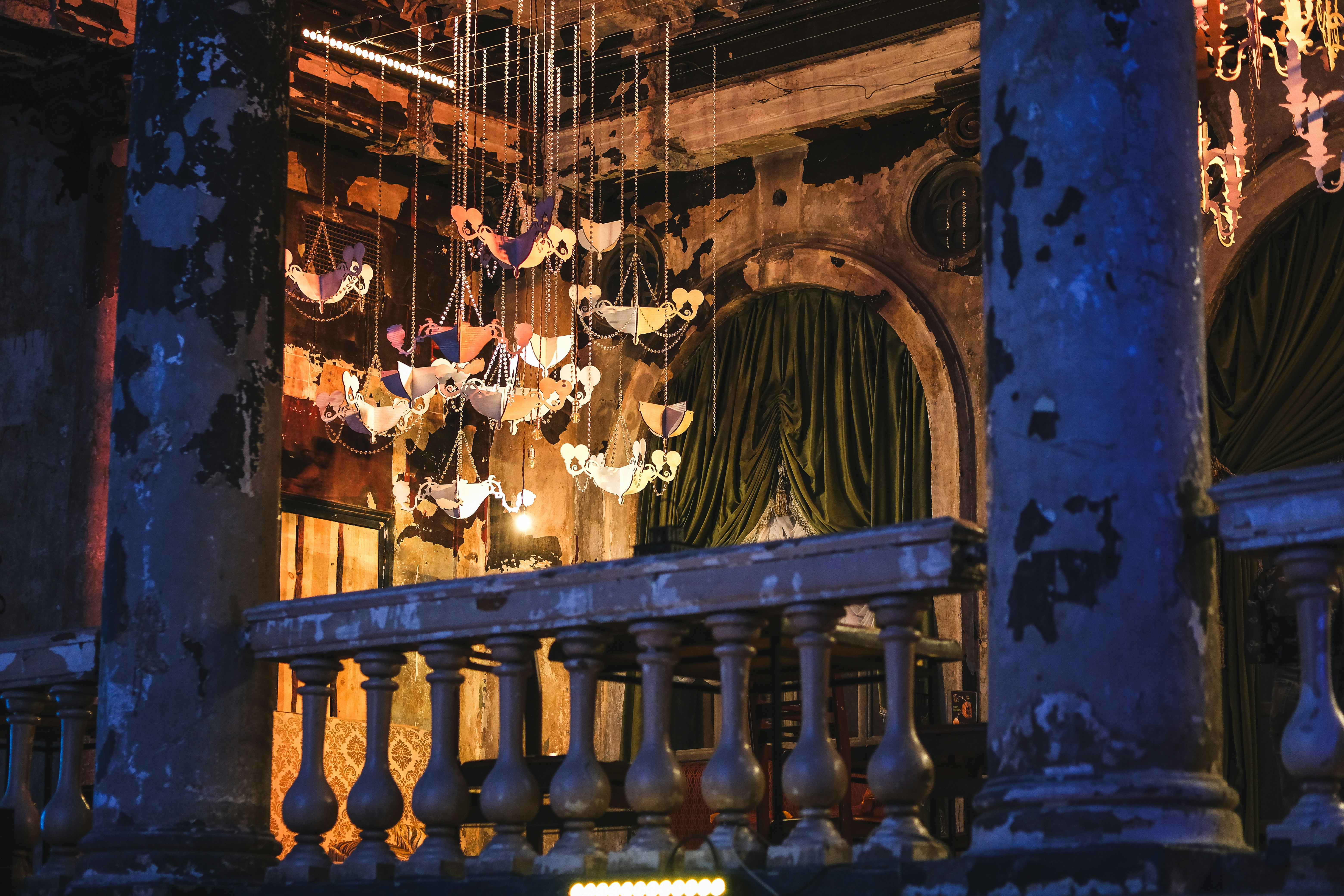 Ornate chandeliers hang in a dimly lit, vintage room.