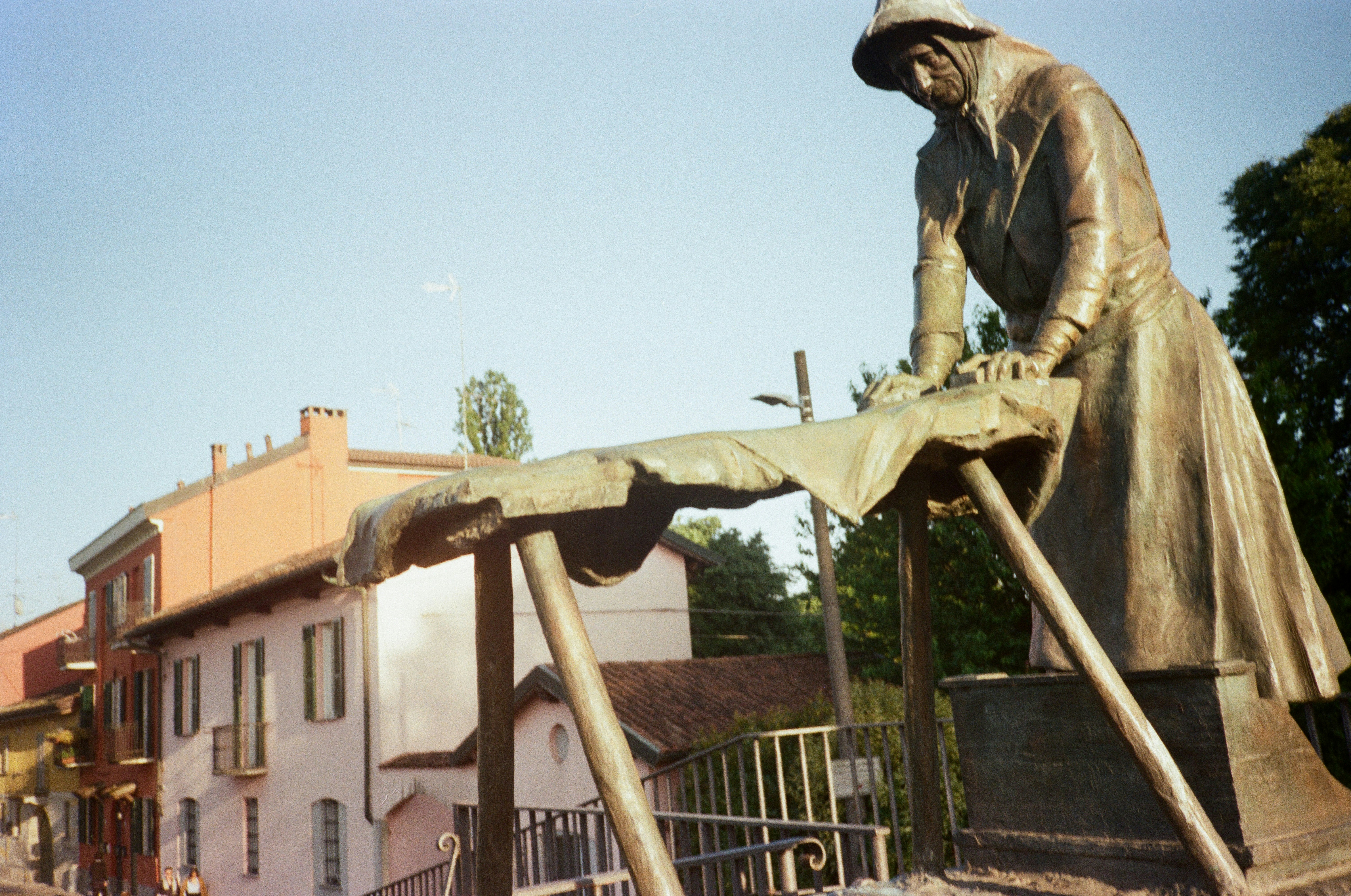 Bronze statue of a man ironing clothes outdoors