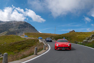 Red sports car driving on a mountain road.