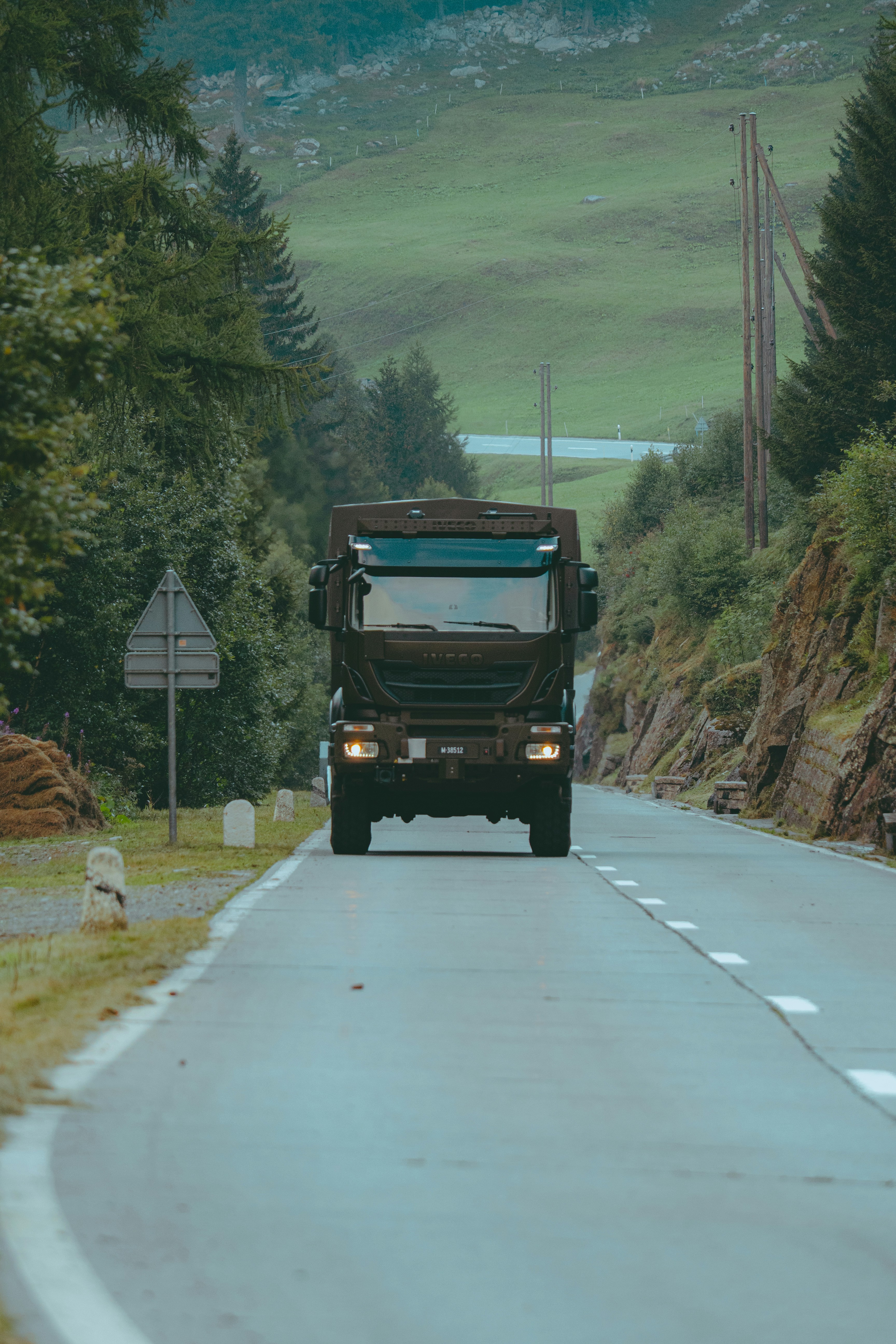 A dark truck drives down a winding mountain road.