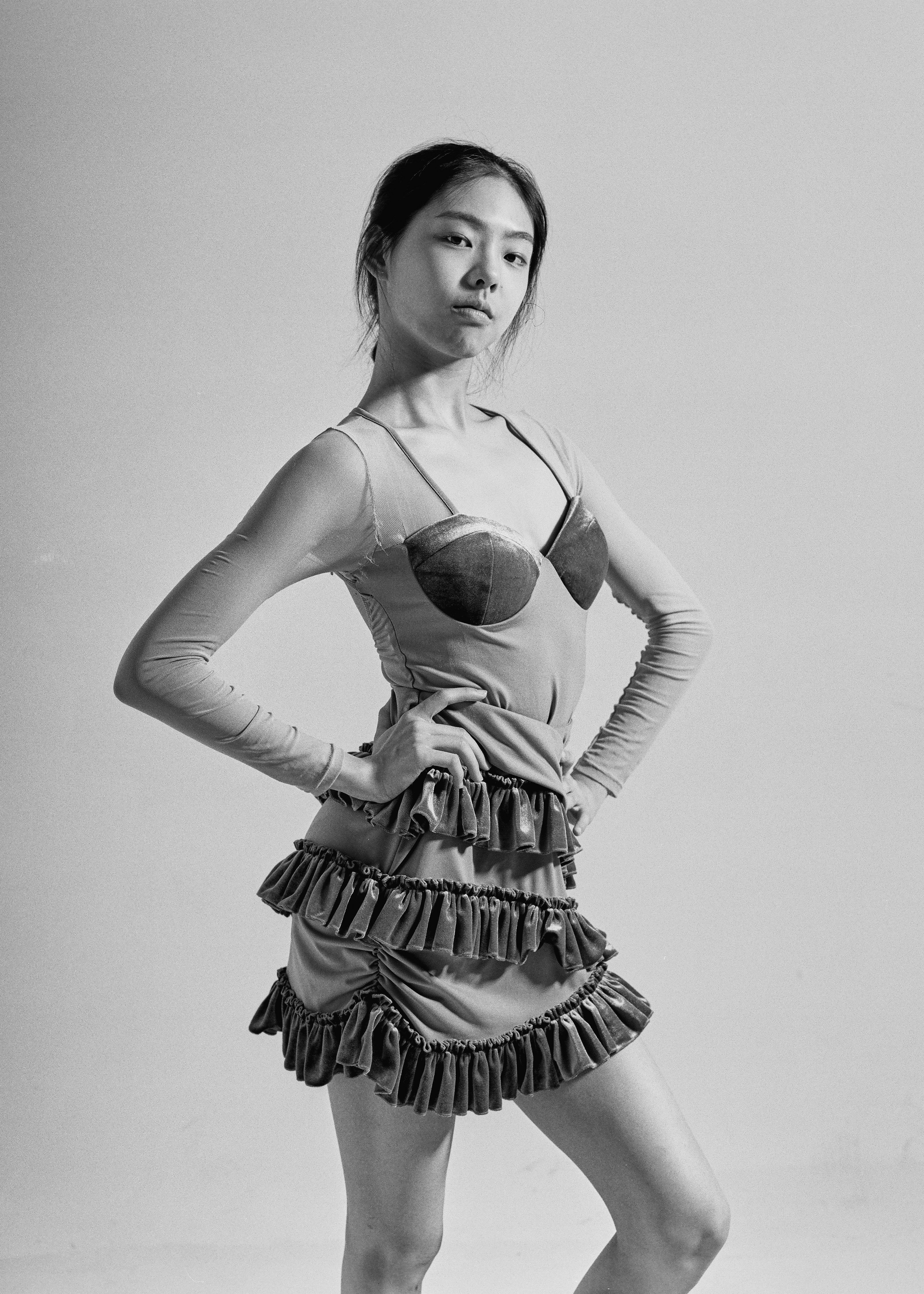 Woman in a ruffled dress with hands on hips.