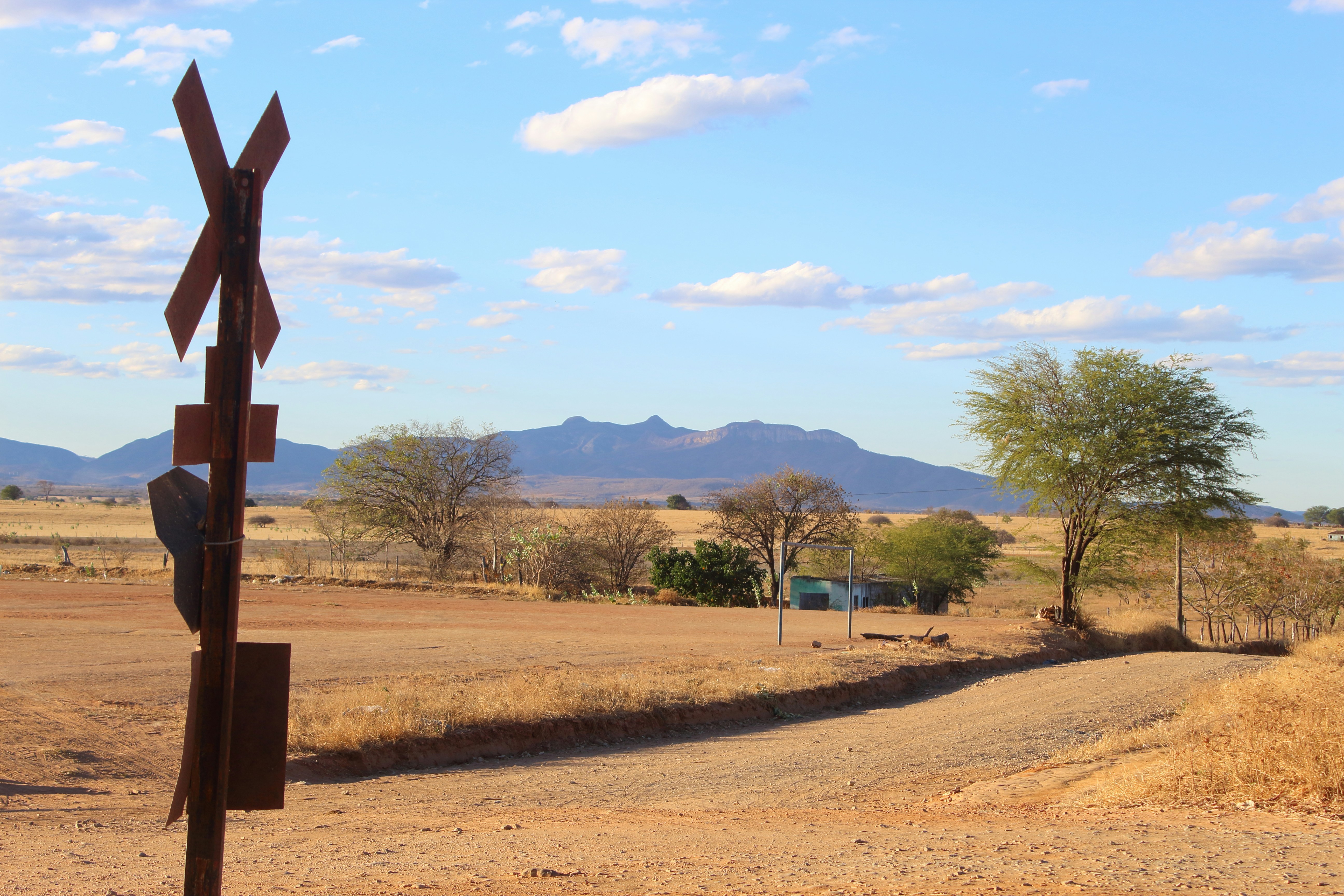 Rural landscape with railroad crossing sign and mountains.