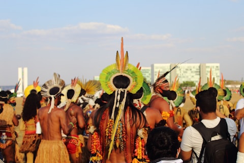 Indigenous people in traditional attire gather outdoors.