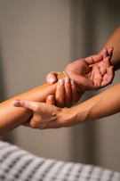 Hands massaging a person's forearm with gentle pressure.