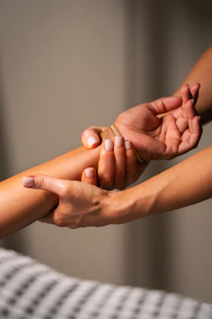 Hands massaging a person's forearm with gentle pressure.