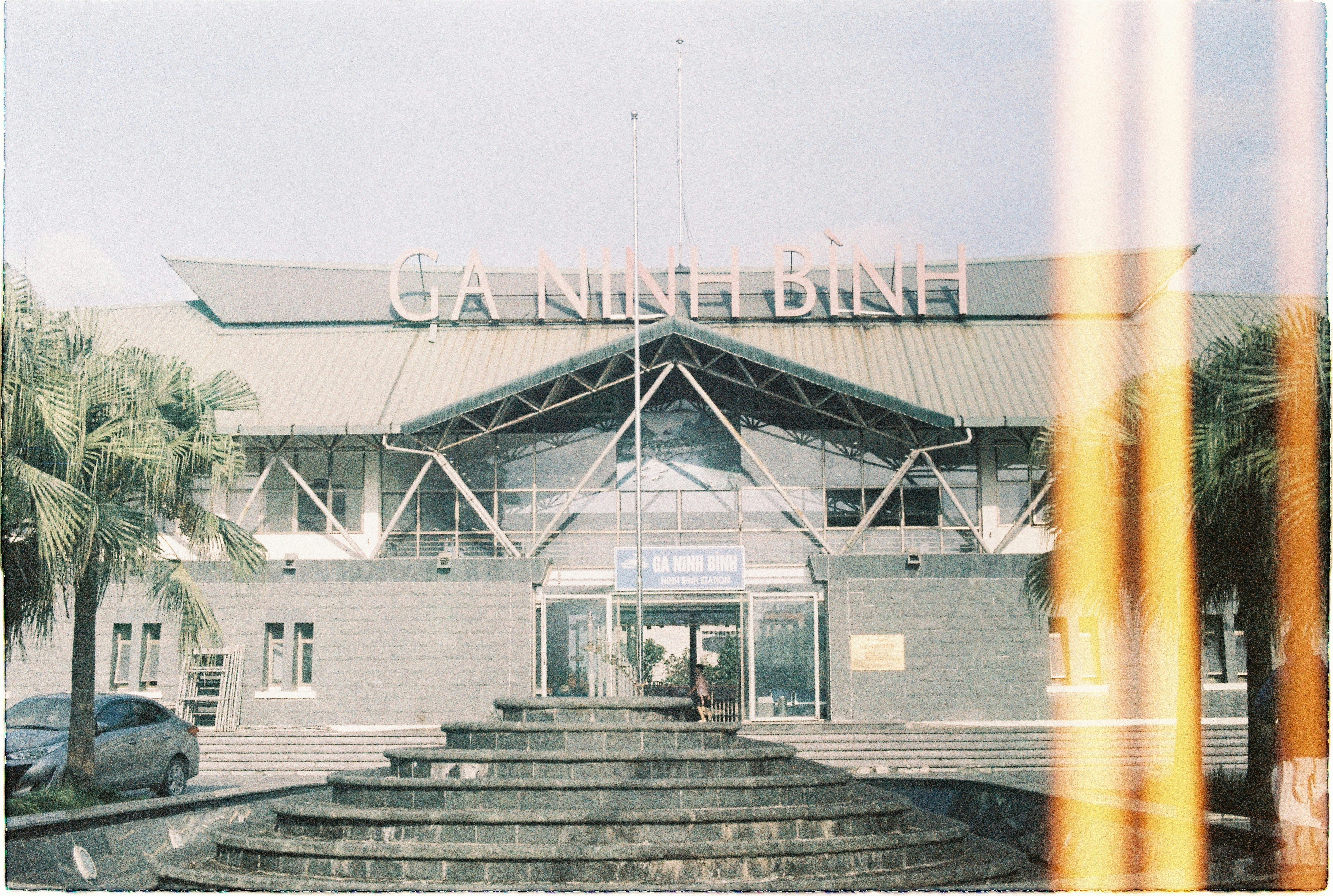 Modern building entrance with wide stairs and palm trees