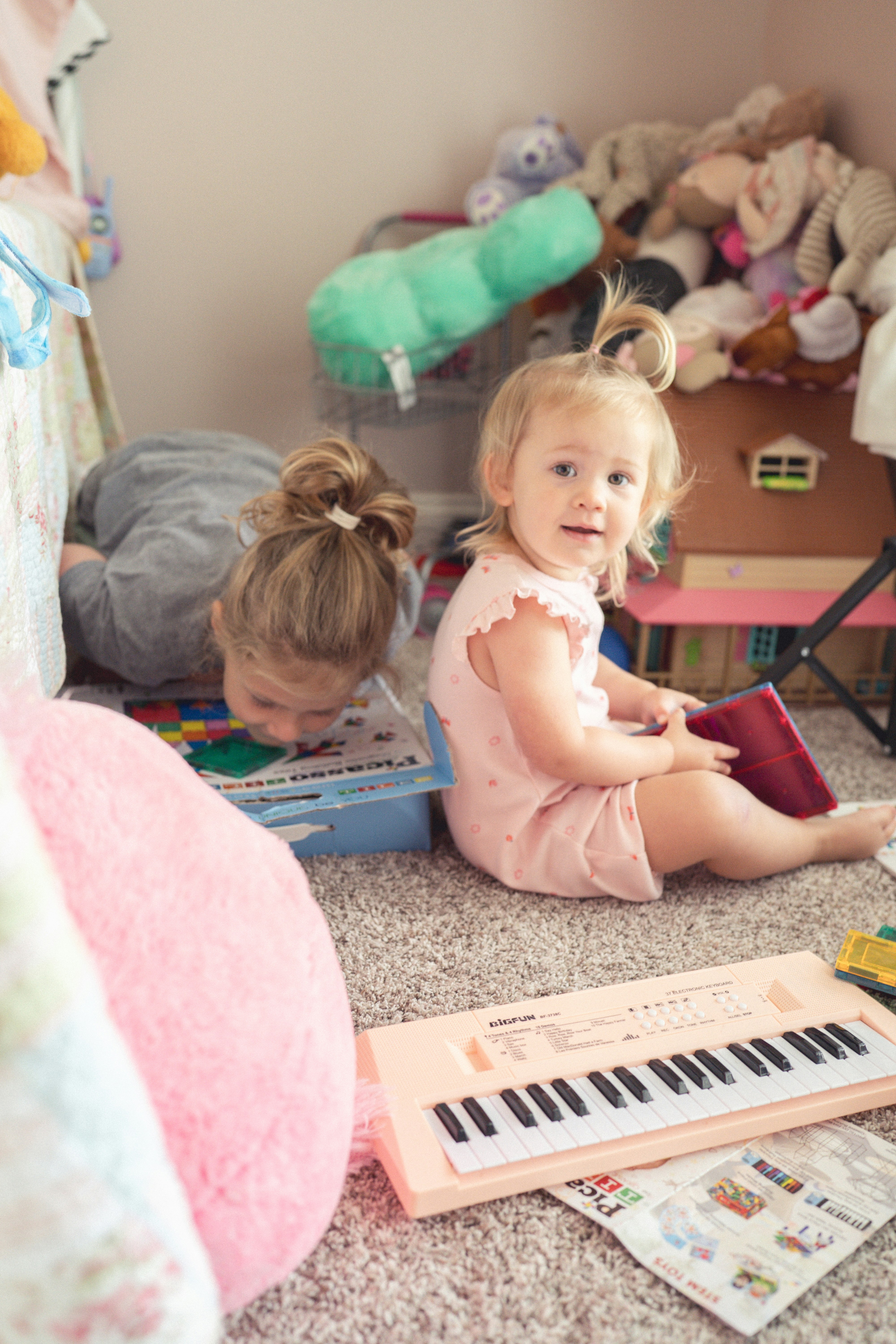 Two young children playing with toys on the floor.