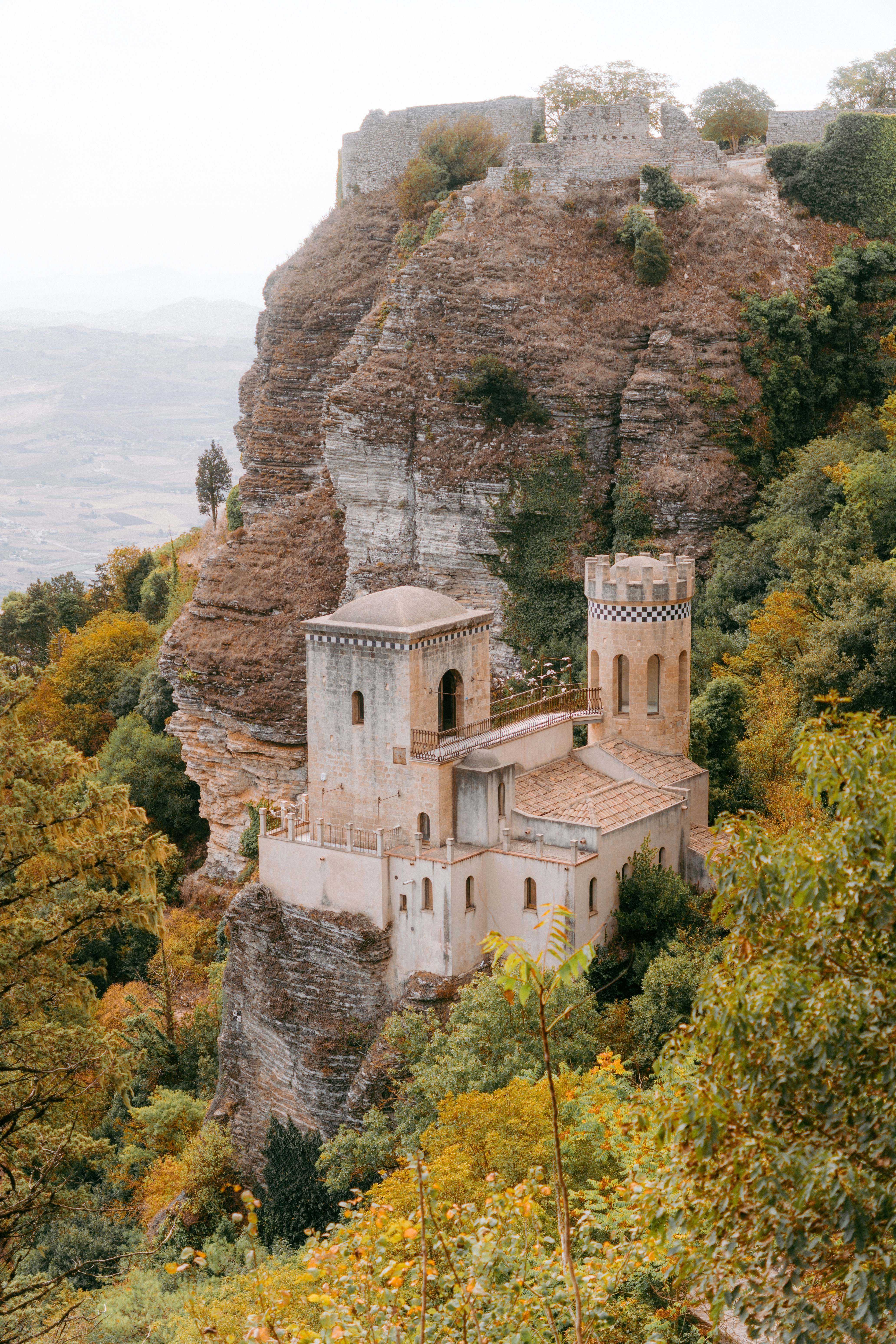 Castle on a rocky cliff surrounded by trees.