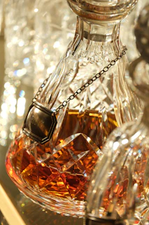 Crystal decanter filled with amber liquid and chain.