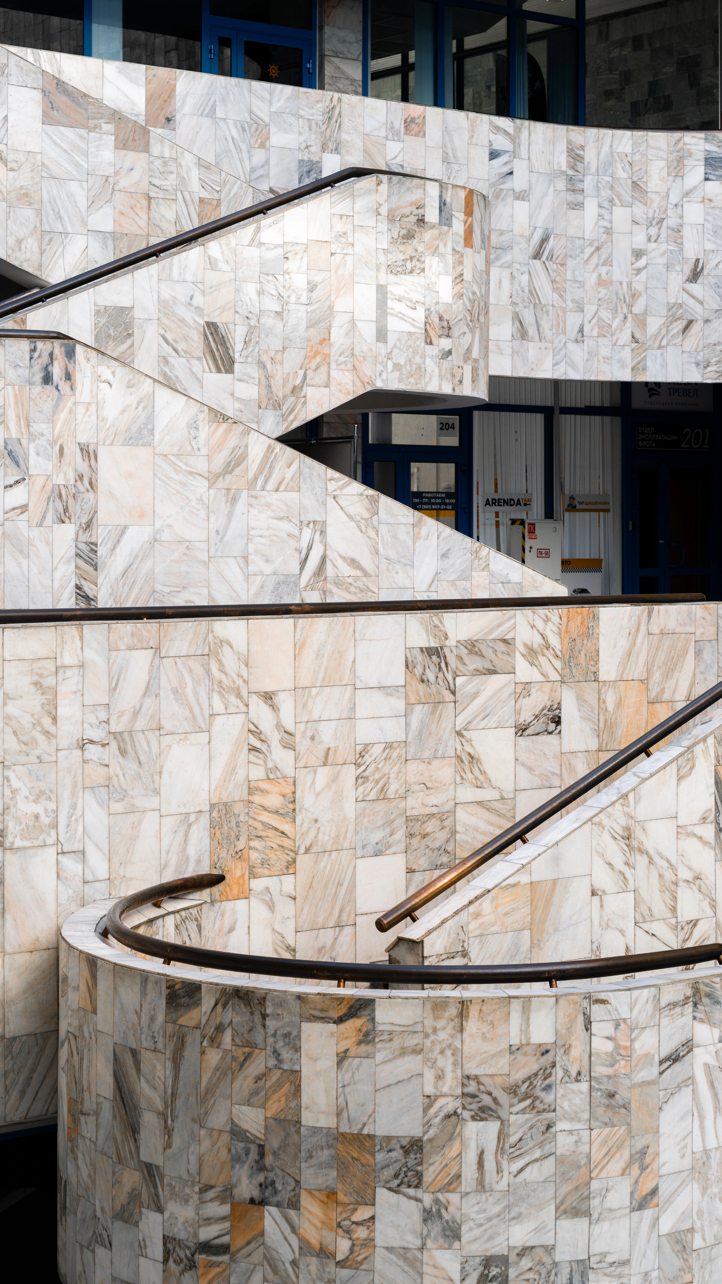 High-end minimalist architectural interior with sculptural marble staircase and warm neutral plaster walls