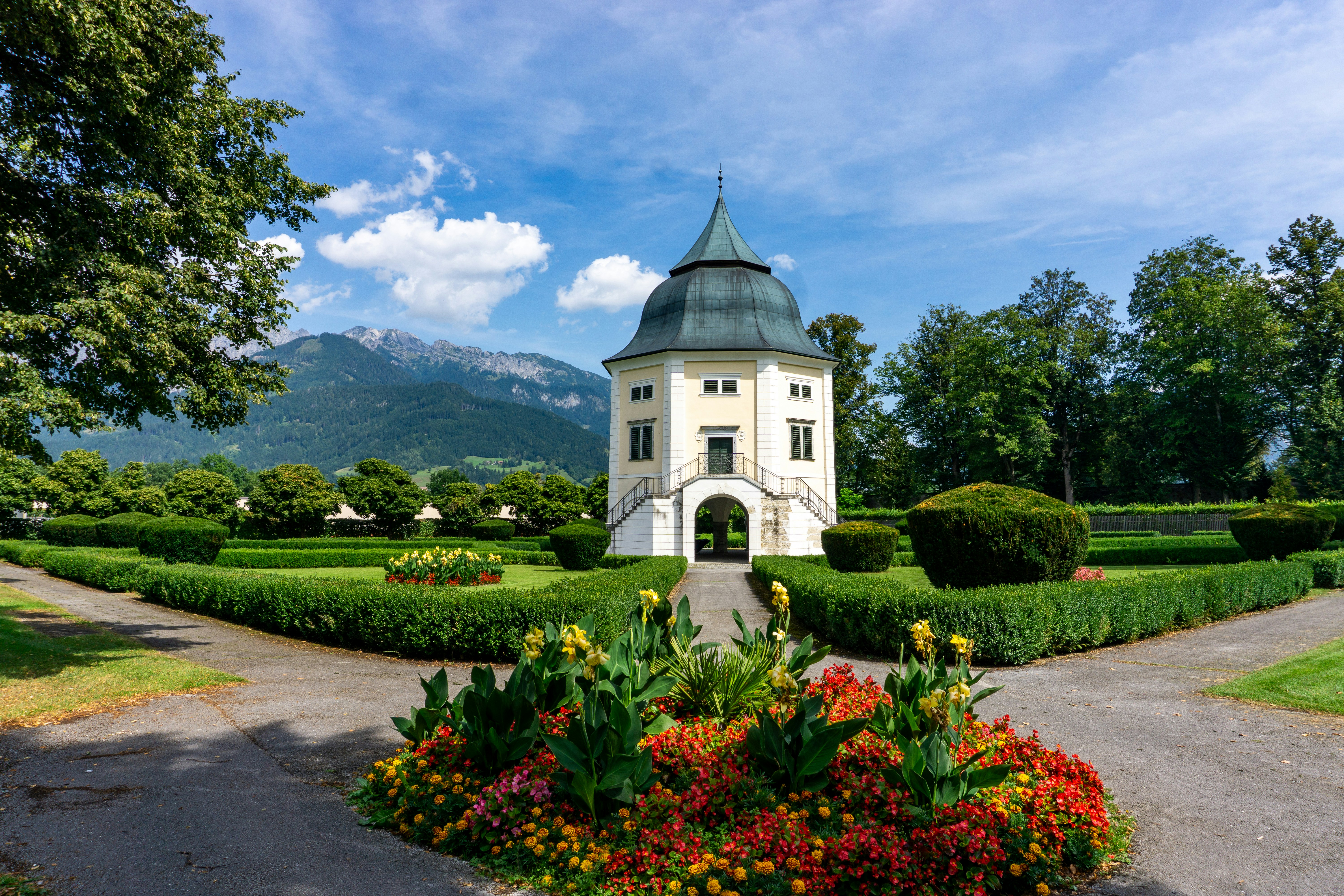 산을 뒤로하는 무성한 정원의 하얀 정자.
