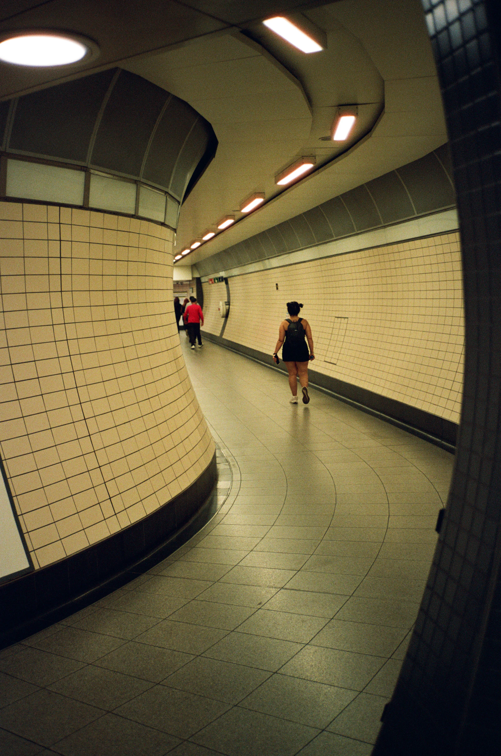 A well-lit underground pedestrian tunnel with curved tiled walls, similar to the corridors that make up Toronto's PATH