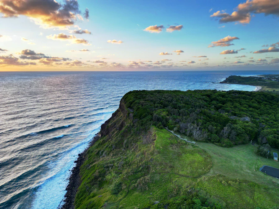 Green coastal cliffs at Lennox Head glowing at sunset above the ocean
