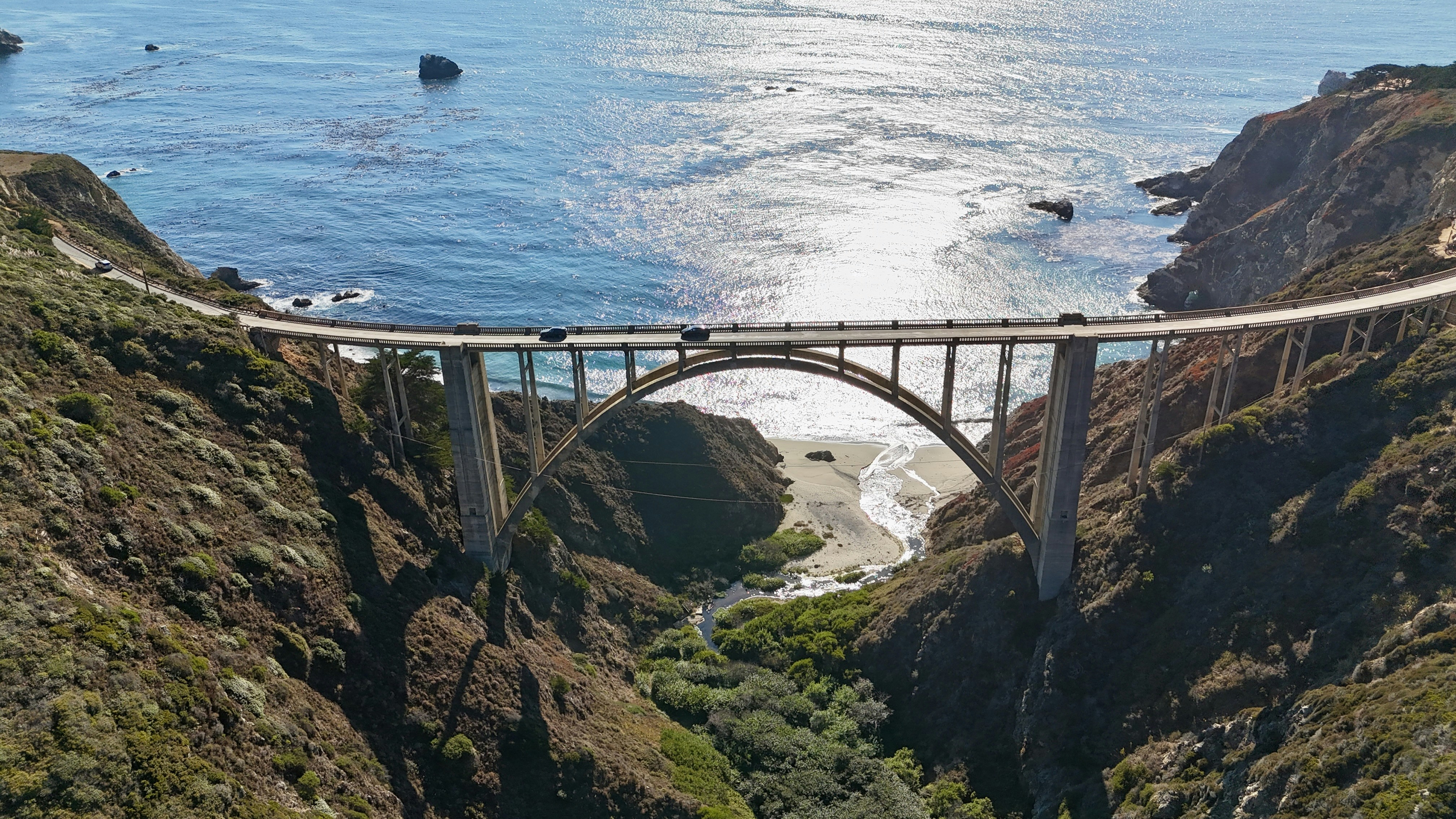 Cars crossing a scenic bridge over a coastal canyon