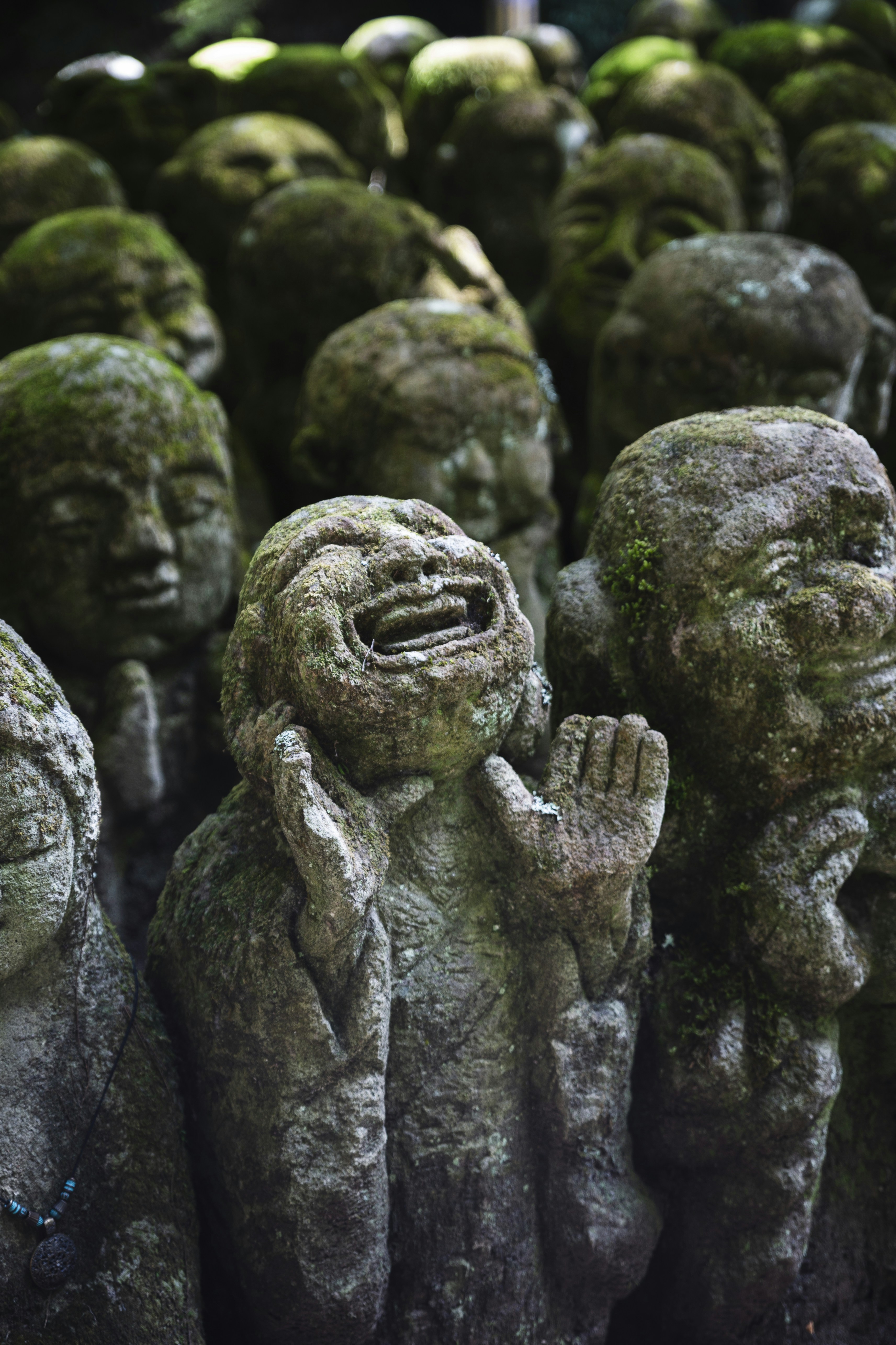 Moosbewachsene Steinstatuen mit ausdrucksstarken Gesichtern